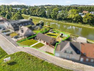 Deze <strong>zeer goed onderhouden gelijkvloerse woning</strong> is gelegen op een<strong> mooi perceel van 937 m²</strong> in Heestert, op de grens met Zwevegem-Knokke, en geniet van een bijzonder <strong>aangename ligging langs het kanaal Bossuit-Kortrijk</strong>.<br />De woning ligt rustig <strong>teruggetrokken van de straat</strong> en combineert deze groene ligging met een <strong>vlotte bereikbaarheid richting Kortrijk en de belangrijkste invalswegen en autosnelwegen</strong>.<br />Dankzij de praktische indeling, drie slaapkamers en volwaardige tuin is dit een comfortabele woning op een<strong> unieke locatie aan het water</strong>.<br /><br /><u><strong>Indeling</strong></u><br />Via de inkomhal met apart toilet kom je binnen in de woonkamer met eetplaats en zithoek.<br />Aansluitend bevindt zich de keuken. De nachthal geeft toegang tot drie slaapkamers en een badkamer.<br />Verder beschikt de woning over een praktische inpandige garage met wasplaats en een ruime zolder die heel wat extra bergruimte biedt.<br />Achteraan bevindt zich de volwaardige tuin met een rustgevend zicht op het kanaal.<br />Het nabijgelegen jaagpad langs het kanaal Bossuit-Kortrijk vormt bovendien een ideale uitvalsbasis voor mooie wandel- en fietstochten langs het water.<br /><br /><u><strong>Technisch</strong></u>
<ul>
<li>Dakisolatie aanwezig</li>
<li>EPC: 459 kWh/(m² jaar) – de woning valt onder de renovatieverplichting</li>
<li>Mogelijkheid om mits beperkte energetische ingrepen aan de renovatieverplichting te voldoen</li>
<li>Niet gelegen in overstromingsgevoelig gebied</li>
<li>Regenwaterput van 10.000L</li>
</ul>
<u><strong>Troeven</strong></u>
<ul>
<li>Zeer goed onderhouden gelijkvloerse woning</li>
<li>Mooi perceel van 937 m²</li>
<li>Prachtige ligging langs het kanaal Bossuit-Kortrijk</li>
<li>Rustig teruggetrokken van de straat</li>
<li>3 slaapkamers op het gelijkvloers</li>
<li>Volwaardige tuin met zicht op het water</li>
<li>Vlotte toegang tot het jaagpad</li>
<li>Praktische garage met wasplaats</li>
<li>Ruime zolder</li>
<li>Vlotte ontsluiting richting Kortrijk en autosnelwegen</li>
</ul>
<u><strong>Contact</strong></u><br />Contacteer Aaron gerust voor meer info of een rondleiding: 0471 89 28 25 - aaron@real-immo.be.<br />Ontdek zelf de rust en unieke ligging van deze woning. <strong>Tot binnenkort!</strong>