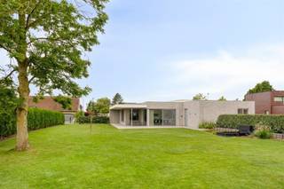 Recente, rustig gelegen laagbouwvilla die momenteel ingericht is en gebruikt wordt als yogacentrum. Deze energiezuinige woning is mits een kleine aanpassing de perfecte bungalow voor wie liever geen trappen meer neemt en gehecht is aan ruimte, licht en comfort. Indeling: ruime inkomhal met vestiaire en toilet, zonnige living met aansluitend een grote ingerichte keuken en berging. Er zijn verder 2 grote slaapkamers, extra toilet en een derde kamer die erop voorzien is om in te richten als badkamer. Buiten is er een mooi aangelegde tuin met een groot, deels overdekt, terras. Er zijn tevens 7 aangelegde parkeerplaatsen. De woning is voorzien van domotica, vloerverwarming/koeling met warmtepomp op basis van geothermie, waterverzachter, zonnepanelen, alarminstallatie, regenwaterput en grondwaterput, kortom volledig futureproof! Door het lage epc is er nog een vrijstelling van de onroerende voorheffing, tevens is er nog 8 jaar garantie op het gebouw.