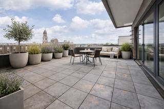 IN OPTIE: kevin@wellimmo.net voor meer info! Bekijk alvast de videotour, grondplan, EPC, asbestattest en de EK via de Wellimmo-site  (‘documenten')<br /><br />Op een absolute topligging langs de Leien, met een panoramisch zicht over de volledige stad en het KMSKA, bevindt zich dit uitzonderlijke penthouse. De combinatie van licht, zon, adembenemende zichten en een kwalitatieve totaalrenovatie maakt dit appartement bijzonder gegeerd binnen zijn segment. Gelegen op de bovenste verdieping van een goed onderhouden gebouw, bereikbaar met de lift tot de 7de verdieping + 1 trap. Wat u daarvoor in de plaats krijgt? Het echte penthousegevoel: maximale privacy, rust en een overvloed aan natuurlijk licht.<br /><br />Met een bew. opp. van ca. 75 m² werd het appartement bijzonder efficiënt ingedeeld. De leefruimte met open, volledig geïnstalleerde keuken baadt in het licht en sluit naadloos aan op het ruime, vergunde zonneterras (ca. 25 m²) aan de voorzijde. Hier geniet u van een panoramisch zicht over de stad van ’s ochtends tot zonsondergang.<br /><br />Aan de achterzijde bevindt zich de slaapkamer met aansluitend de badkamer (ligbad/douchecomb), én toegang tot een tweede terras (niet vergund, maar volledig functioneel). Ook hier geniet u van open zichten en een extra buitenruimte in alle rust. Wakker worden met zicht over de stad vanuit uw bed? Dit is zo’n plek waar het elke dag realiteit wordt! Verder beschikt het appartement over een aparte wasplaats, gastentoilet en tal van ingemaakte kasten. De afwerking is hedendaags en kwalitatief, met o.a. parket en maatwerkmeubilair, waardoor het volledig instapklaar is.<br /><br />• Toplocatie op de Leien, pal op het Zuid — één van de meest gegeerde buurten van Antwerpen<br />• Gunstig EPC: B (136 kWh/m²)<br />• Panoramische zichten langs beide zijden + uitzonderlijke lichtinval<br />• Ruim, vergund zonneterras (ca. 25 m²) + tweede 'terras' voor extra buitenbeleving<br />• Kwalitatieve totaalrenovatie<br />• De maandelijkse lasten bedragen +-180€ incl: syndicus, blokpolis, waterverbruik, onderhoud, spaarfonds,....<br />• Ideaal voor eigen bewoning of als investering<br /><br />Een zeldzame combinatie van locatie, licht, luxe en buitenruimte — dit is wonen op niveau!<br /><br />Voor meer info of een bezoek: info@wellimmo.net of 03/225.00.68<br /> 