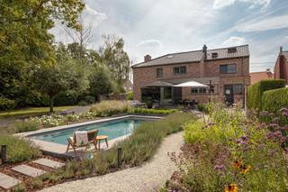 <p><strong>Volledig gerenoveerde woning met 5 slaapkamers, zwembad en prachtig aangelegde tuin op 1.643 m².</strong></p>
<p><strong>BEKIJK ZEKER ONZE (VIRTUELE) GRONDPLANNEN EN ATTESTEN VOOR DE INDELING EN EXTRA INFORMATIE.</strong></p>
<p>Bent u op zoek naar een ruime en volledig gerenoveerde woning met een uitzonderlijk aangename tuin en een vrij uitzicht achteraan? Dan is deze karaktervolle woning in Hombeek zeker een bezoek waard. <br /><br />Met een bewoonbare oppervlakte van maar liefst 359 m², vijf slaapkamers, twee badkamers, een afzonderlijke bureauruimte en dressing biedt de woning bijzonder veel ruimte voor een gezin of kan dienst doen als kangoeroewoonst. De woning onderging in 2014 een totaalrenovatie en combineert het karakter van de oorspronkelijke woning met een hedendaagse en verzorgde afwerking. De ruime leefruimte met haard sluit mooi aan op de lichtrijke eetplaats en de volledig uitgeruste keuken met kookeiland. Grote raampartijen zorgen voor een sterke verbinding met het terras en de fraai aangelegde tuin. <br /><br />Buiten vormt het perceel van 1.643 m² een absolute troef. De tuin werd in 2019 volledig aangelegd en beschikt over verschillende terrassen, een vijver, volwassen beplanting en een verwarmd zwembad van 8 x 4 meter. Achteraan geniet u bovendien van een prachtig open zicht over de omliggende velden.<br /><br />Ook technisch staat de woning sterk met EPC-label A, conforme elektriciteit, 26 zonnepanelen, ventilatiesysteem D en een laadpaal. Het asbestattest vermeldt de woning als asbestveilig.<br /><br />De woning combineert een rustige, groene ligging met een uitstekende bereikbaarheid dankzij de vlotte verbinding naar Mechelen, de A12 en de E19. Winkels, scholen en openbaar vervoer bevinden zich bovendien in de nabije omgeving.</p>
<p><strong>ALGEMENE KENMERKEN:</strong></p>
<ul>
<li><span>Totaalrenovatie uitgevoerd in 2014</span></li>
<li>Rustige, landelijke ligging in Hombeek met een uitstekende bereikbaarheid naar Mechelen, de A12 en de E19, en nabij winkels, scholen en openbaar vervoer</li>
<li>5 slaapkamers, 2 badkamers, aparte bureauruimte en dressing</li>
<li>Royale leefruimte, eetkamer en volledig uitgeruste keuken</li>
<li>Prachtig aangelegde tuin met verschillende terrassen, vijver en volwassen beplanting</li>
<li>Verwarmd zwembad (warmtepomp, 2025) van 8 x 4 meter, aangelegd in 2019</li>
<li>Open en landelijk uitzicht achteraan</li>
<li>Voldoende parkeerplaatsen</li>
</ul>
<p><strong>TECHNISCHE KENMERKEN:</strong></p>
<ul>
<li>Zeer gunstige EPC-score: 69 kWh/(m²/jaar) - Label A</li>
<li>Elektrische installatie woning conform AREI - 3-fasen</li>
<li><span>Asbestveilig</span></li>
<li>Centrale verwarming op aardgas</li>
<li>26 zonnepanelen (2019) – opbrengst van ca. 7.000 kWh/jaar</li>
<li><span>Ventilatiesysteem type D</span></li>
<li><span>Laadpaal</span></li>
<li>Regenwaterput van 10.000 liter</li>
<li>Elektrische zonnescreens en rolluiken aan de zuidkant</li>
<li><span>Videofoon</span></li>
<li><span>Aansluiting alarminstallatie</span></li>
</ul>
<p><strong>INDELING:</strong></p>
<p><u>Gelijkvloers</u></p>
<ul>
<li>Ruime inkomhal met apart toilet</li>
<li>Grote leefruimte met zithoek en haard</li>
<li>Lichtrijke eetplaats met directe verbinding naar terras en tuin</li>
<li>Ruime, volledig uitgeruste keuken met centraal kookeiland</li>
<li><span>Afzonderlijke bureau- of praktijkruimte</span></li>
<li>Eerste badkamer met douche, toilet en lavabo</li>
<li><span>Wasplaats en berging</span></li>
</ul>
<p><u>Eerste verdieping</u></p>
<ul>
<li><span>Nachthal</span></li>
<li><span>Meerdere ruime slaapkamers</span></li>
<li><span>Dressing</span></li>
<li>Tweede badkamer met inloopdouche, ligbad en lavabo</li>
<li><span>Afzonderlijk toilet</span></li>
</ul>
<p><u>Tweede verdieping</u></p>
<ul>
<li><span>Ingerichte zolderruimte / slaapkamer</span></li>
</ul>