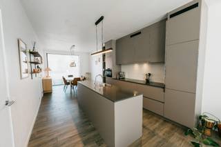 <p>EPC A++ | 3 slaapkamers | dressing | zonnepanelen | laadpaal | passieve vloerkoeling</p><p>3 jaar vrijgesteld van KI</p><p>Deze recente en volledig instapklare BEN-woning is gunstig gelegen op korte afstand van het centrum, winkels, scholen en openbaar vervoer. Dankzij de vlotte verbinding met de autostrade zijn ook omliggende gemeenten en steden gemakkelijk bereikbaar. De woning combineert een uitstekende ligging met hedendaags wooncomfort en een uitzonderlijk energiezuinig karakter.</p><p>Indeling</p><p>Via de inkomhal betreedt u de woning, waar een praktische ingebouwde vestiairekast voldoende ruimte biedt voor jassen en schoenen. Op het gelijkvloers bevindt zich eveneens een apart gastentoilet.<br />Verder bevinden zich hier de lichtrijke leefruimte, eetkamer en keuken. De verschillende leefruimtes sluiten mooi op elkaar aan en zorgen voor een aangenaam en ruimtelijk geheel.</p><p>Op de verdieping bevinden zich drie slaapkamers.<br />De grootste slaapkamer beschikt over een aansluitende dressing. De twee overige slaapkamers zijn elk ca. 10 m² groot. De badkamer heeft bad/douche.<br />Daarnaast is er op deze verdieping ook een tweede, apart toilet.</p><p>Buitenruimte<br />Ook buiten is het aangenaam vertoeven. Het terras is voorzien van een elektrische luifel, ideaal om op zonnige en warme dagen extra schaduw te creëren.<br />In de tuin bevindt zich bovendien een praktisch tuinhuis, ideaal voor het opbergen van fietsen, tuinmateriaal en andere spullen. Achter het huis bevindt zich nog een autostaanplaats die je langs achter kan betreden.</p><p>Energiezuinig en futureproof<br />Met een EPC-label A++ scoort deze woning bijzonder sterk op vlak van energiezuinigheid. De woning is uitgerust met zonnepanelen, een laadpaal en passieve vloerkoeling, wat zorgt voor een combinatie van een laag energieverbruik en aangenaam wooncomfort.</p><p>Bijzonderheden<br />• EPC-label A++<br />• Recente en volledig instapklare woning<br />• 3 slaapkamers<br />• Aansluitende dressing<br />• Badkamer met bad/douche<br />• 2 aparte toiletten, één op het gelijkvloers en één op de ver</p>