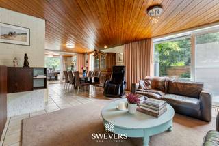 Voor meer info en foto’s, surf naar www.swevers.be – Deze ruime open bebouwing aan de Langerloweg 39 in Genk biedt een uitstekende combinatie van ruimte, ligging en mogelijkheden. Gelegen in een rustige woonomgeving op slechts 1,8 km van het centrum, geniet u hier van een vlotte bereikbaarheid met scholen, winkels, horeca, openbaar vervoer en de autosnelweg in de nabije omgeving. De woning werd gebouwd in 1969 en beschikt over een bewoonbare oppervlakte van 184 m² op een royaal perceel van 945 m². Dankzij vernieuwde ramen (2008) en een gerenoveerde badkamer (2009) zijn reeds belangrijke investeringen uitgevoerd. Binnen verwelkomt een ruime inkomhal u naar de lichtrijke woonkamer van circa 38 m², waar grote raampartijen zorgen voor een aangename sfeer en veel natuurlijk licht. De aansluitende keuken van ongeveer 14 m² biedt de mogelijkheid om een moderne leefkeuken te creëren met directe toegang tot terras en tuin. Op de verdieping bevinden zich vier slaapkamers, ideaal voor gezinnen of wie extra ruimte wenst voor een bureau of hobbykamer. De vernieuwde badkamer is uitgerust met een ruime douche en wastafel. Daarnaast is er een afzonderlijk toilet aanwezig. Een absolute troef is de volledige onderkeldering van 103 m², inclusief een inpandige garage van 44 m² met plaats voor twee wagens. Deze extra ruimte biedt tal van mogelijkheden voor opslag, hobby’s of werkruimte. Buiten geniet u van een verzorgde tuin met oostelijke oriëntatie, veel privacy en een aangename groene omgeving. Een ideale gezinswoning voor wie ruimte zoekt en deze verder naar eigen smaak wil moderniseren. <br /><br />Dit pand is onderworpen aan de renovatieverplichting van de Vlaamse overheid voor residentiële gebouwen (behoudens bij sloop binnen 5 jaar na de aankoop). Consulteer voor meer informatie de website van het Vlaams Energie- en Klimaatagentschap via https://www.vlaanderen.be/een-huis-of-appartement-kopen/renovatieverplichting-voor-residentiele-gebouwen.<br /><br />Voor meer informatie, bel 011 255 155. Bron bewoonbare oppervlakte: EPC – verslag.