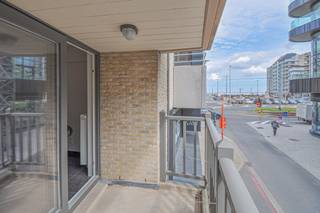 Centraal gelegen appartement met zijdelings zeezicht in het commercieel centrum. Indeling: Inkomhal met toilet. Lichtrijke leefruimte met toegang...