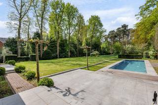 <p>Op wandelafstand van de winkels in het centrum, aan mooie laan én op een prachtig perceel grond (<strong>ca. 4.899 m²)</strong>, zeer sfeervolle en instapklare villa met achterliggende <strong>guesthouse (heden pilatesstudio + conciërgewoning) en buitenzwembad.<br /></strong><br /><strong>De gelijkvloerse verdieping: </strong></p>
<p>- Hal/entree op terracotta vloer met gastentoilet en handenwasser <br />- Een royale woonkamer (ca. 68m²) op parket met hout gestookte open haard en grote raampartijen met zicht op de tuin<br />- Een leefkeuken (ca.58m²) op terracotta vloer met gashaard, <strong>2 keukeneilanden</strong> met dubbele gootsteen, inductie kookvuur, vaatwasser en bargedeelte (4 pers.), kastenwand met 2 koelkasten+diepvries (Neff), 2 ovens en een Miele stoomoven.<br />- Een bureau/tv kamer (ca. 31m²) op parket met hout gestookte open haard en inbouwkasten<br />- Een slaapkamer (ca.18m²) op terracotategel met inloopdouche, toilet en lavabo<br />- Zij-ingang via de garage: een inpandige garage (ca.47m²) voorzien van 2 elektrische poorten, 2 uitgietbakken, en ingemaakte kasten, elektra, <br />water en verwarming. <br />- Een kelder (ca.100m²) met o.a. <strong>wijnkelder</strong>, technische ruimte, waterontharder en veel opslagruimte <br /><br /><strong><u>De eerste verdieping is op visgraatparket: <br /></u></strong>- Een nachthal op parketvloer<br />- Een <strong>royale hoofdslaapkamer (ca.27m²) met gashaard en royale dressing (ca.36m²)</strong><br />- Een ensuite marmeren hoofdbadkamer (ca.13m²) met dubbele lavabomeubel, ligbad, inloopdouche en toilet, ingemaakte kast<br />- Twee slaapkamers (ca.28m² en 17m²) <br />- Een vijfde slaapkamer (ca.13m²) met douchekamer (ca. 6m²), toilet en lavabo<br />- Een badkamer (ca.13m²) met ligbad, inloopdouche, dubbele lavabo en toilet<br /><br /><strong><u>De tweede verdieping is volledig voorzien van visgraatparket en onderliggende houtroostering:</u></strong><br />- Een zesde slaapkamer (ca.22m²) met ensuite douchekamer voorzien van inloopdouche, toilet en lavabo<br />- hobbykamer/wasplaats/berging met ingemaakte kastenwand<br /><br /><strong>Tuinhuis/guesthouse:</strong><br />Keuken voorzien van Siemens gasfornuis, gootsteen, ijskast. Douchekamer voorzien van douche, lavabo, toilet, sauna zowel gewone sauna als infraroodsauna en fitness/pilatesruimte voorzien van sporthal en balletbar. Via vaste trap naar bovenliggende verdieping waar zich de slaapkamer bevindt. <br /><br /><strong><u>Vernieuwingen:</u></strong></p>
<p>In 2010: totaalverbouwing.<br />In 2022 is het rolluik alsook de motor van het zwembad vernieuwd, alsook zijn de parketvloeren gelegd op de 1<sup>ste</sup> en 2<sup>de</sup> verdieping, keuken deels vernieuwd, OH in de keuken geplaatst, deels nieuwe terracotategel in de keuken, etc.<br />In 2023: is de elektra herkeurd<br />In 2024: is het huis volledig herschilderd (plafonds en muren) incl. de dakgoten.</p>
<p><strong><u>Algemeen:</u></strong></p>
<p>- Verwarming op gas (Remeha) d.m.v. radiatoren en vloerverwarming in het bureel, de living en deels in de keuken. Optima boiler.<br />- Alarmsysteem d.m.v. ruimtedetectie, rookmelders aangesloten op de alarminstallatie, veiligheidsdeur, domotica, waterontharder, rolluiken, vliegenramen, blokdeuren.<br />- Oprit te bereiken via automatische toegangspoort<br />Kelder bestaande uit kelder (berging) en kruipkelder, gescheiden rioleringssysteem, regenwaterput (niet in gebruik)<br />- Centrale ligging t.o.v. het centrum, openbaar vervoer, winkels en scholen</p>
<p><strong><u>Tuin:</u></strong></p>
<p>Prachtig aangelegde diepe omheinde tuin welke volledige privacy biedt.<br />Verwarmd buitenzwembad (chloor + ionisatie ) van 14m op 4m en ca. 1,5m diep. (vernieuwd rolluik en motor).<br />Diverse terrassen zowel bij het bijgebouw, als bij de villa waaronder eveneens een overdekt terras met vaste zitbank, heatstrip en muziek, zonnetent.<br />Achterliggende houtberging, tweede tuinhuis<br />Sproei-installatie</p>