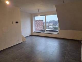 <p><span><strong>Nieuwbouwappartement met 2 slaapkamers, terras en 2 autostaanplaatsen.</strong></span><br /><br />Ontdek dit moderne duplexappartement, doordacht ingedeeld voor comfort en praktisch wonen. Bij binnenkomst betreedt u een inkomsas, die niet alleen de toegang biedt tot de tweede slaapkamer – ideaal als bureau, kinder- of gastenkamer – maar ook tot het gastentoilet. Vanuit de inkomsas loopt u door naar de open keuken, geplaatst langs één wand en volledig uitgerust met alle hedendaagse toestellen zoals inductiekookplaat, koelkast met vriesvak en vaatwasser. Ruime opbergmogelijkheden maken het geheel volledig functioneel.</p>
<p>De keuken gaat naadloos over in de lichtrijke leefruimte, met grote ramen die een aangenaam groen uitzicht bieden en een open, luchtige sfeer creëren. Vanuit de leefruimte heeft u toegang tot het noordwestelijk georiënteerde dakterras, perfect om te genieten van de namiddag- en avondzon.</p>
<p>Via de interne trap bereikt u de eerste verdieping, waar de ruime hoofdslaapkamer wacht, samen met de badkamer voorzien van modern badkamermeubel met enkele wastafel en een aparte douchecabine.</p>
<p>Praktisch ingedeeld, is de warmtepomp slim geplaatst onder de trap, waardoor de bergruimte groot en praktisch blijft, en tevens voorzien is van de aansluiting voor wasmachine en droogkast.</p>
<p>Het appartement beschikt bovendien over twee autostaanplaatsen: één vooraan op de kiezel en één veilig binnenin de residentie. De autostaanplaatsen beschikken tevens over de mogelijkheden tot het opladen van elektrische of hybride voertuigen.</p>
<span><strong>Huurprijs</strong></span>: €1150,00 per maand.<br /><br /><span><strong>Beschikbaarheid</strong></span>: bij oplevering (medio maart 2026).<br /><br /><span><strong>EPB in opmaak.</strong></span>