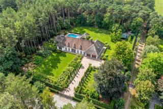 <p>Na het geruisloos openen van de statige poorten bemerk je direct vanuit de gracieuze oprijlaan met statige antieke straatlantaarns en parking tot de in detail mooi aangelegde tuin van deze majestueuze villa op ongeveer 11.000 m² eigen grond op een toplocatie in de prestigieuze villawijk op enkele minuten van de NL-grens. Nieuwsgierig naar de rest lopen we gewoon achterom tot bij het verwarmd zwembad met super uitnodigend pool house en vele terrassen te ontdekken. Gasten nodig je hier met plezier uit en is ideaal voor feestjes. Ook de zonnestand van een zuid-west oriënterende tuin doet vrolijk mee. Het feest blijft maar doorgaan als we nog een praktische schuur bemerken (50 m²) als berging die je ook kan bereiken via een zij-inrit. </p><p>De kers op de taart is toch wel het smaakvol gerenoveerd (2021) hoofdgebouw met ongeveer 720 m² inhoud. Binnenkomend in de ontvangsthal begin je al direct te watertanden, want deze sfeer en top afwerking springt direct in het oog. Bij de leefkamers met gezellige zithoeken en een echte antieken open haard wil je al graag neervlijen en genieten van de omgeving. De taart en ander lekkers voor de feestelijkheden zal je met plezier bereiden in de doordacht ontworpen luxe keuken, die van alle leuke snufjes is voorzien zoals een sierijskast voor wijn, koffiebar, ….en bij de ontbijttafel of grote eetplaats met prachtige panoramische zichten en openslaande deuren zal je dit gaarne nuttigen. Er is zelfs aan een bijkeuken gedacht en een grote waskamer, vele extra inbouwkasten zijn er ook bewonderen. De kwaliteit, vloerverwarming en discrete airco's zorgen voor een extra luxueus gevoel. </p><p>Natuurlijk mag vooraan je ook een statig bureel verwachten waar thuiswerken een andere dimensie wordt en deze paalt aan de vestiaire en gastentoilet voor de bezoekers of klanten. Voor een slaapkamer op het gelijkvloers hoef je zelfs geen extra kosten te maken, want die kan ook voor deze en andere doeleinde worden gebruikt. Achteraan is er nog een extra berging en een tweede toilet. De grootse inpandige garage kan tot 4 (!) wagens herbergen, alsook met een extra berging.</p><p>Vanuit de bovenverdieping op de vide en kijkend naar de woonkamer ervaar je net dat tikkeltje meer klasse, dat als VIP kan worden waargenomen. Hier bevinden zich de vele ruime slaapkamers, verschillende comfort badkamers, een fitnesszaal met sauna, maar vooral de knappe dressing met vele maatkasten springen extra in het oog. </p><p>Buiten is er een groots en verwarmd zwembad met roldek en omgeven door zonneterrassen en een sfeervol poolhouse, ideaal om gasten te ontvangen of jezelf te verwennen. Het buitenterras is voorzien van zonneschermen en een aantrekkelijke open haard voor een BBQ of voor de avondfrisheid wat voor te blijven.</p><p>Achter op het perceel vind je nog een omheind terrein met schuilhut voor herten, of andere dieren, een paardestal voor 2 paarden met berging,….</p><p>Kortom een genot voor alle zintuigen en kom langs om dit alles zelf te aanschouwen. het is immers de (kleine) moeite dubbel en dik waard!</p><p>Bijzonderheden:</p><p>- Onzichtbare airco-units - vloerverwarming<br />- Zij-ingang via aanpalend openbaar wandelpad<br />- EPC label B<br />- Geen asbest en elektriciteit is conform<br />- Achteraan het perceel is bos en agrarisch gebied <br />- Op enkele minuten van de NL grens en 25 minuten van Eindhoven<br />- Beregeningsinstallatie - Aangelegde en volledig omheinde tuinen<br />- Parking<br />- Beveiligd met camera's en alarm<br />- Vele zonnepanelen en laadpaal in de garage<br />- Vele op maat gemaakte inbouwkasten <br />- Plannen op onze site verkrijgbaar<br />- (Snel) beschikbaar in overleg</p><ul><li>2 toegangspoorten achteraan</li></ul><p> </p><p><span><strong>Extra troef:</strong> de aankoop van deze eigendom kan desgewenst ook gebeuren via een overdracht van de aandelen van de vennootschap waarin de woning zich bevindt. In dat geval is een aankoop zonder registratierechten mogelijk</span></p><p><span><span>Infoplicht: Vg, Wg (parkgebied) Gmo, Gvkr, Vv Dit is geen aanbod, alle informatie is steeds onder voorbehoud van materiële vergissingen en/of wijzigingen. De vermelde oppervlaktes zijn louter indicatief.</span></span></p>