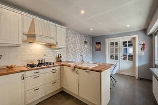<p><strong>Op enkele minuutjes wandelen van het centrum van Herenthout, in de Molenstraat, staat deze halfopen bebouwing te wachten op een nieuwe toekomst. De woning vraagt om een grondige renovatie, maar wie graag zelf keuzes maakt én een huis naar eigen smaak vormgeeft, kan hier volop aan de slag. Met twee slaapkamers, een zolder die verder afgewerkt kan worden en een zuidgerichte tuin is er alvast een mooie basis om op verder te bouwen. Kom binnen…</strong></p><p><strong>Binnenkomen via de keuken</strong><br />Je komt de woning binnen via de keuken aan de zijkant. Die is halfopen en heeft een werkblad met een warme uitstraling. Ernaast is er plaats voor een eettafel, zodat koken en tafelen hun eigen plek krijgen - zonder helemaal van elkaar gescheiden te zijn.<br />Dubbele deuren naar de leefruimte<br />Vanuit de keuken geven dubbele deuren toegang tot de woonkamer. Daar vind je een zithoek met open haard én ruimte voor een bureau. Zo kan de leefruimte verschillende functies combineren: ontspannen na een lange dag, gezellig samen zitten of even rustig aan het werk.</p><p><strong>Een badkamer met een knus hoekje</strong><br />De badkamer heeft een bad dat half verscholen zit achter een muurtje. Dat geeft de ruimte een gezellig, beschut karakter. Ook deze plek kan mee opgenomen worden in de renovatieplannen, zodat je de woning verder kunt afstemmen op je eigen smaak.</p><p><strong>Boven valt er nog iets af te werken</strong><br />De woning telt twee slaapkamers. De kleinere slaapkamer heeft een ingebouwde kastenmuur, wat meteen een praktische opbergoplossing oplevert. Daarnaast is er een zolder die nog verder afgewerkt kan worden. Een extra ruimte om bij je plannen te betrekken en op termijn naar eigen wensen, plannen en dromen in te vullen.</p><p><strong>Achteraan: extra veel plaats</strong><br />Achteraan bevindt zich een grote bergplaats of garage, die ook dienst kan doen als werkhuis. Handig voor wie graag ruimte heeft om spullen op te bergen, te klussen of materiaal een vaste plek te geven.</p><p><strong>Een zonnige tuin</strong><br />Ook buiten liggen er mogelijkheden. De tuin is zuidgericht, een fijne troef voor wie graag van de buitenruimte geniet én een echte zonneklopper is.</p><p>Interesse?Lier@ugly.be</p>