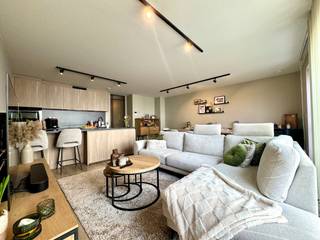 BENIEUWD? VRAAG EEN AFSPRAAK AAN VIA WWW. HILLEWAERE.BE EN KLIK OP DE RODE KNOP 'BEZOEK AANVRAGEN'.<br /><br />Van klasse gesproken! Dit nieuwbouw appartement is gelegen op het gelijkvloers in een mooi complex in de dorpskern van Tielen, nabij winkels en openbaar vervoer. Smaakvol en luxueus afgewerkt! <br /><br />Indeling:<br />Aan de achterzijde bevindt zich de woonkamer die uiterst licht is door de brede raampartij. Hier is voldoende ruimte om een zithoek te creëren en een eettafel te plaatsen. Van hieruit kan je naar het ruime en uiterst gezellige terras (18m²) in het groen. De open keuken met eiland is toch wel de blikvanger! Prachtig werkblad en voorzien van een inductievuur, vaatwasser, combi-oven en koelkast. De smaakvolle verlichting krijg je er als bonus bij. <br /><br />Via een zwart stalen glazen deur kom je tot de hal. Hier bevindt zich de badkamer. Deze is ingericht met een wastafel, inloopdouche en praktische ingemaakte kast. De wasplaats heeft voorziening voor wasmachine en droogkast. De leidingen zijn hier netjes weggewerkt achter een wand. Verder is er nog een apart toilet en 2 slaapkamers met elektrische rolluiken.<br /><br />De huur omvat tevens een ondergrondse parkeerplaats (10) met aansluitend een zeer ruime private kelderberging (8).<br /><br />Bijzonderheden:<br />- Duurzame materialen<br />- Verlichting aanwezig<br />- Zonnepanelen<br />- Vloerverwarming over gans het appartement<br />- Vliegenramen<br />- Lift aanwezig<br />- Servicekosten: 75 €/maand<br />- Beschikbaar vanaf 1 mei