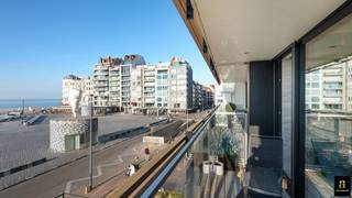 <p>Ontdek dit unieke plateau-appartement in de prestigieuze residentie “Midan”, gelegen op het Rubensplein. Met een gevelbreedte van 12,5 meter en een verfijnde afwerking door interieurarchitect Frederic Kielemoes, straalt dit appartement pure luxe en elegantie uit. Hoogwaardige materialen zoals terrazzo, Italiaanse marmer, travertin en smeedwerk, gecombineerd met maatwerk inbouwkasten, zorgen voor een tijdloze en stijlvolle uitstraling.</p>
<h3><strong>Indeling:</strong></h3>
<ul>
<li>
<p><strong>Royale inkomhal</strong> met vestiaire en gastentoilet.</p>
</li>
<li>
<p><strong>Ruime leefruimte</strong> met zitgedeelte en bureauhoek, genietend van een adembenemend frontaal zeezicht.</p>
</li>
<li>
<p><strong>Gashaard</strong> voor extra sfeer en warmte.</p>
</li>
<li>
<p><strong>Grote schuiframen</strong> naar het voorterras (13m²) met panoramisch zicht op zee.</p>
</li>
<li>
<p><strong>Open keuken</strong> voorzien van hoogwaardige Miele-toestellen, aansluitend een ruime bijkeuken/berging.</p>
</li>
<li>
<p><strong>Aparte wasplaats</strong> voor extra praktisch comfort.</p>
</li>
</ul>
<p>Achteraan bevinden zich vier volwaardige slaapkamers, elk geschikt voor een dubbel bed en met directe toegang tot het achterterras:</p>
<ul>
<li>
<p><strong>Master bedroom</strong> met en-suite badkamer (ligbad, lavabo, douche) en apart toilet.</p>
</li>
<li>
<p><strong>Tweede douchekamer</strong> in de nachthal met apart toilet.</p>
</li>
<li>
<p><strong>Vierde slaapkamer</strong> beschikt over een eigen badkamer.</p>
</li>
</ul>
<p>Een unieke woonbeleving met een ongeëvenaarde ligging, sublieme afwerking en maximaal ruimtelijk comfort. Bij het appartement kan een garagebox voor 4 wagens gekocht worden.</p>