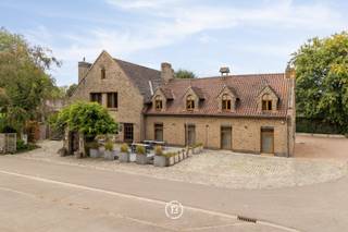 Deze statige villa is gelegen op een toplocatie en beschikt over ca. 575 m² bewoonbare oppervlakte, wat tal van mogelijkheden biedt voor zowel privé- als professioneel gebruik. Dankzij de royale oppervlaktes, veelzijdige indeling en professionele uitrusting leent het pand zich onder meer voor horecafaciliteiten, een combinatie van wonen en werken, een kangoeroeconcept of een andere invulling op maat.<br /><br />Momenteel is de villa als volgt ingedeeld:<br /><br />Op het gelijkvloers bevindt zich een ruime polyvalente ruimte, aangevuld met gastentoiletten, een grote professionele keuken en praktische stockagevoorzieningen.<br /><br />De eerste verdieping omvat opnieuw een ruime polyvalente ruimte, die naar wens verder kan worden ingericht met meerdere slaapkamers en badkamers. Daarnaast bevindt zich hier een volwaardig apart appartement, bestaande uit een slaapkamer, badkamer, uitgeruste keuken en leefruimte.<br /><br />Een ruim balkon biedt bovendien een aangename buitenruimte en vormt een mooie verbinding met de groene omgeving. Rondom de villa bevindt zich een verzorgde tuin met vijver, die de eigendom een bijzondere charme en rust geeft.<br /><br />Verder beschikt deze woning over een dubbele garage en ruime oprit. <br /><br />De combinatie van de uitzonderlijke oppervlakte, de flexibele indeling, het ruime balkon en de aangename tuin met vijver maakt van deze eigendom een veelzijdig geheel met tal van mogelijkheden voor wie op zoek is naar een karaktervolle en ruime eigendom met potentieel.