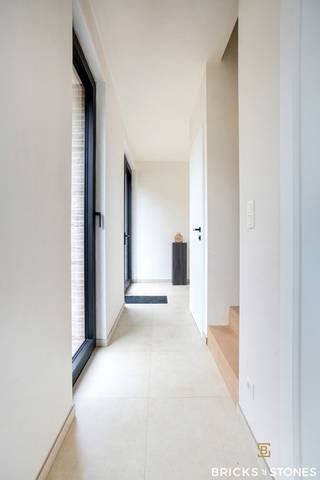 Gelegen in een rustige en groene wijk in Beerzel, vinden we deze prachtige nieuwbouwwoning met een uitstekende verbinding naar de omliggende gemeenten.<br /><br />Via de aparte inkomhal, met ingemaakte vestiaire, betreden we de woning. Achteraan, in alle rust en met zicht op de tuin, bevindt zich de ruime woon- en leefruimte. Grote raampartijen zorgen hier voor een overvloed aan natuurlijk licht en geven rechtstreeks toegang tot het terras en de zonnige tuin. De woonkamer sluit naadloos aan bij de eetruimte en de open keuken. Deze keuken is volledig uitgerust met kwalitatieve toestellen (koelkast met vriezer, combi-oven en inductiekookplaat) en beschikt over een praktisch kookeiland met spoelbak en vaatwasser.<br /><br />Aansluitend vinden we een handige berging, waar alle technieken netjes zijn weggewerkt. Bovendien is er hier voldoende plaats voor extra opbergruimte en de aansluiting voor wasmachine en droogkast.<br /><br />Op de verdieping ontdekken we drie volwaardige slaapkamers. De master bedroom (ca. 20 m²) beschikt over een en-suite badkamer met dubbele wastafel, douche én bad. De twee overige slaapkamers (ca. 18 en 19 m²) zijn eveneens ruim en delen een tweede, zeer praktische badkamer. Elke kamer heeft er een eigen wastafel, terwijl de douche gedeeld kan worden – ideaal als kinder- of gastenbadkamer.<br /><br />Deze woning werd afgewerkt met hoogwaardige materialen en oog voor detail, met technieken die garant staan voor duurzaam en energiezuinig wonen. Dankzij vloerverwarming, warmtepomp en zonnepanelen kiest u hier voor een toekomstgerichte thuis waarin comfort en kwaliteit centraal staan.<br /><br />Een woning die klasse, comfort en know-how perfect combineert.