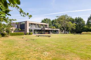 Deze stijlvolle, moderne villa uit 2018 is gelegen op een uitzonderlijk breed perceel van maar liefst 5.016 m² en biedt een unieke combinatie van hedendaags wooncomfort, privacy en een groene, landelijke omgeving. De tijdloze architectuur, gekenmerkt door grote raampartijen, zorgt voor een overvloed aan natuurlijk licht en creëert een harmonieuze verbinding tussen binnen en buiten.<br /><br />Het royale perceel vormt een absolute meerwaarde voor wie houdt van ruimte en natuur. Dankzij de omvang en de rustige ligging biedt het tal van mogelijkheden voor dierenliefhebbers en paardenliefhebbers, met voldoende plaats om dieren aan huis te houden of het terrein naar eigen wens in te richten.<br /><br />Ook voor wie wonen en werken wil combineren, is deze woning bijzonder geschikt. Er zijn twee afzonderlijke ruimtes voorzien die perfect kunnen dienen als praktijk, bureau of kantoor aan huis.<br /><br />De leefruimte werd ontworpen met oog voor openheid, licht en wooncomfort. De volledig uitgeruste keuken is voorzien van hoogwaardige Gaggenau-toestellen en een Quooker-kraan. Vanuit de keuken en de aangrenzende leefruimte geniet u van een prachtig, weids uitzicht over de zuidoost georiënteerde tuin en de achterliggende natuur, waardoor elk seizoen optimaal beleefd kan worden.<br /><br />Aansluitend aan de keuken bevindt zich een ruime berging die eveneens rechtstreeks bereikbaar is via de carport. Daarnaast beschikt de woning over talrijke maatkasten, een tweede grote berging en een aparte wasruimte met douche, waardoor functionaliteit en opbergruimte ruimschoots aanwezig zijn.<br /><br />Het wooncomfort wordt verder versterkt door een uitgebreid domoticasysteem, camerabewaking, een alarmsysteem en een geïntegreerde muziekinstallatie die doorheen de volledige woning voor extra gebruiksgemak en sfeer zorgen.<br /><br />De villa telt vijf volwaardige slaapkamers en twee stijlvolle badkamers. De master bedroom beschikt over een ensuite badkamer en een ruime dressing, met een rustgevend uitzicht op het omliggende groen.<br /><br />Ook op technisch vlak voldoet deze woning aan de hoogste verwachtingen. Dankzij het gunstige energielabel A en de conforme elektrische installatie is deze villa volledig klaar voor de toekomst.<br /><br />Deze uitzonderlijke eigendom biedt een zeldzame combinatie van moderne architectuur, hoogwaardig wooncomfort, een prachtig natuurzicht en een royaal perceel met tal van mogelijkheden voor gezinnen, zelfstandigen én dieren- of paardenliefhebbers.