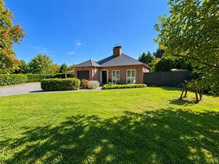 <p><span>Deze charmante, traditioneel gebouwde gedeeltelijk gelijkvloers villa ligt aan de zuidelijke rand van het zeer gegeerde Bois de Strihoux. </span></p><p><span>De villa omvat een inkomhal van 4 m² met gastentoilet (travertinvloer) die toegang geeft tot een leefruimte van 30 m² – eveneens met travertinvloer – waar een inbouwhaard op hout voor een gezellige sfeer zorgt. Aansluitend bevindt zich een moderne Ixina-keuken (10 m²) die naadloos overgaat in een lichtrijke veranda van 25 m² (voorzien van airconditioning), met kamerhoge ramen en een dakraam met drievoudige beglazing. Deze recente veranda vormt een natuurlijke overgang naar het beschutte terras en de grote tuin met op het zuiden oriëntatie. </span></p><p><span>Het slaapgedeelte is bereikbaar via een hal van 4 m² met luxe vinylvloer en omvat een hoofdslaapkamer van 14 m² met maatkasten, een tweede slaapkamer met airco (9 m²), een moderne inloopdouchekamer (6 m²) en een bureau (7 m²); vanuit het bureau leidt een trap naar een ruime derde slaapkamer van 26 m² met Velux-dakramen. In de betegelde garage van 16 m² bevinden zich de technische installaties, de boiler, de wasruimte en een koele berging. De woning werd in 1989 door de eigenaars zelf gebouwd (Huysmans Eeklo). Tot de uitrusting behoren onder meer een nieuwe condenserende mazoutketel (Riello, 2023), 10 zonnepanelen, een elektrische boiler, een B&G-inbouwhaard op hout, een regenwaterput, een grote carport voor twee wagens en twee tuinhuizen. Bieden vanaf € 550.000. Voor informatie en bezichtigingen kunt u bellen naar 02/355.50.55.</span></p><p><span> </span></p><p><span> </span></p>