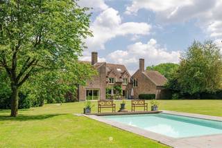 <p><span>Bent u op zoek naar een unieke eigendom waar rust, privacy en ruimte harmonieus samenkomen? Dan zal deze uitzonderlijke landelijke villa in het hart van het glooiende Waaslandse landschap u ongetwijfeld weten te bekoren.</span></p><p><span> </span></p><p><span>Verscholen op de tweede bouwlijn en omringd door prachtige volwassen bomen strekt deze exclusieve eigendom zich uit over maar liefst ruim 2 hectare. De zeldzame combinatie van een idyllische, groene omgeving en een uitstekende bereikbaarheid maakt van dit domein een absolute buitenkans.</span></p><p><span> </span></p><p><span>De belangrijkste troeven in een notendop:</span></p><ul><li><span>Exclusief domein van 21.677 m² met aangelegde tuin, weilanden, zwembad en poolhouse.</span></li><li><span>Toplocatie: uiterst rustig gelegen en toch op slechts 3 minuten van de oprit van de E17, met een vlotte verbinding naar Gent, Antwerpen en Brussel.</span></li><li><span>Prachtige beplanting met waardevolle bomen en een sfeervolle vijver.</span></li><li><span>Zeer ruime villa met een bewoonbare oppervlakte van ca. 500 m².</span></li><li><span>6 slaapkamers en 2 badkamers.</span></li><li><span>Perfecte zuidwestoriëntatie </span></li></ul><p><span> </span></p><p><span>Via de oprijlaan bereikt u deze karaktervolle villa, die in 1979 degelijk werd gebouwd en doorheen de jaren met zorg werd onderhouden, gemoderniseerd en energetisch geoptimaliseerd.</span></p><p><span> </span></p><p><span>Het gelijkvloers verwelkomt u met een royale inkomhal die toegang biedt tot de leefruimtes. De aparte keuken sluit naadloos aan op de eetplaats en de gezellige zithoek met open haard. Daarnaast is er een afzonderlijke bureauhoek voorzien. Via de grote raampartijen heeft u directe toegang tot het zonnige terras en prachtig zicht op groen, waar binnen en buiten moeiteloos in elkaar overvloeien. Verder beschikt deze verdieping over een praktische koele berging en drie garages.</span></p><p><span> </span></p><p><span>Op de eerste verdieping bevinden zich vier ruime slaapkamers en een grote polyvalente ruimte die zich perfect leent als royale master bedroom, praktijkruimte, aparte bureauruimte of conciërge-/nannyverblijf. Dankzij de mogelijkheid om een bijkomende trap met eigen toegang te voorzien, biedt deze ruimte tal van interessante invullingen.</span></p><p><span> </span></p><p><span>De tweede verdieping vervolledigt het geheel met nog twee bijkomende slaapkamers.</span></p><p><span> </span></p><p><span>Het uitgestrekte domein vormt zonder twijfel één van de absolute blikvangers van deze eigendom. De prachtige volwassen bomen creëren een uniek en groen kader, terwijl het vergunde zwembad met poolhouse uitnodigt om volop te genieten van het buitenleven. </span></p><p><span> </span></p><p><span>Dankzij de ideale zuidwestoriëntatie geniet u hier de hele dag van de zon.</span></p><p><span> </span></p><p><span> De weilanden bieden bovendien tal van mogelijkheden voor paardenliefhebbers of voor wie graag omringd wordt door natuur en openheid.</span></p><p><span> </span></p><p><span>Doorheen de jaren werden verschillende energiebesparende investeringen uitgevoerd, waaronder spouw-, dak- en kelderisolatie alsook hoogrendementsbeglazing.</span></p><p><span> </span></p><p><span>Bent u klaar om het unieke karakter en de uitzonderlijke ligging van deze eigendom zelf te ontdekken? Neem dan vrijblijvend contact op voor een bezoek via <span>pieter@axellenaerts.be</span></span><span>.</span></p>