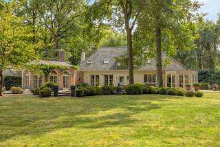 <p>In een doodlopende straat in 's-Gravenwezel bevindt zich deze tijdloze villa op een uitzonderlijk mooi perceel van meer dan 5.000 m² met een straatbreedte van circa 60 meter. De woning grenst rechtstreeks aan een uitgestrekt parkgebied en ligt op wandelafstand van de slotgracht van het Kasteel van ’s-Gravenwezel. Een unieke combinatie van absolute rust, privacy en een vlotte bereikbaarheid naar Antwerpen en de omliggende gemeenten.</p>
<p><strong>GELIJKVLOERS<br /></strong>Riante inkomhal 28 m² op blauwe hardsteen met eiken parket. Aansluitend bevindt zich een gastentoilet met handenwasser en een tweede halgedeelte met trap.</p>
<p>Het bureel van 22 m² met aparte ontvangstruimte leent zich perfect voor comfortabel thuiswerk.</p>
<p>Daarnaast is er een sfeervolle bibliotheek van 13 m² met ingemaakte boekenkast.</p>
<p>De imposante leefruimte van 122 m² op brede eiken parketvloer beschikt over een kastenwand en een inbouwhaard en geniet van een prachtig zicht op de tuin. De eetkamer bevindt zich in een orangerie met haardvuur en grote ramen die uitgeven op het terras en de parktuin.</p>
<p>De landelijke keuken van 25 m² met werkblad in blauwe hardsteen sluit aan op een charmante tuinkamer op parket, eveneens met directe toegang tot de tuin.</p>
<p>Verder op het gelijkvloers bevinden zich een garage van 29 m² en een kelder van 14 m². Het aangelegde terras van 30 m² en de volledig omheinde, fraai aangelegde tuin versterken het gevoel van ruimte en privacy.</p>
<p>Bijkomend is er een eiken bijgebouw met twee overdekte autostaanplaatsen en een afgesloten garage.</p>
<p><strong>Verdieping<br /></strong>De nachthal van 15 m² is afgewerkt met sisal-tapijt.<br />De royale masterbedroom van 56 m² beschikt over een eigen salon, dressing en ensuite badkamer. Daarnaast zijn er 3 bijkomende slaapkamers van 13 m², 13 m² en 17 m².<br />Eveneens is er een aparte strijk- en wasruimte van 12 m² met ingemaakte ladekasten en aansluiting voor wasmachine en droogkast.<br />De 2de badkamer van 11 m² is afgewerkt in natuursteen en uitgerust met lavabo, ligbad en toilet.</p>
<p>Via een vlizotrap bereikt u de zolder van 32 m².</p>
<p><strong>BIJZONDERHEDEN<br /></strong>Cv op aardgas, dubbele beglazing, houten schrijnwerk, alarminstallatie, waterontharder, parlofoon, dimmers, ingebouwde spots, 2 open haarden, tuinverlichting, volledig omheinde tuin met automatische toegangspoort.</p>
<p><strong>POSITIEVE PUNTEN<br /></strong>Absolute toplocatie<br />Gelegen in doodlopende straat<br />Prachtig aangelegde tuin met oprijlaan<br />Rechtstreekse aansluiting op natuur- en parkgebied</p>