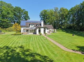 <p><span>Deze karaktervolle woning biedt een unieke combinatie van ruimte, rust en privacy in een groene en landelijke omgeving. Gelegen op een prachtig zuidgericht perceel van maar liefst 2ha 48a 40ca geniet u hier van een uitzonderlijk gevoel van vrijheid en een open zicht op de omliggende weilanden.<br /><br /></span></p><p><span>De woning werd gebouwd in 1980 en in 2003 uitgebreid met een bijkomende aanbouw. Doorheen de jaren werd ze steeds goed onderhouden en afgewerkt met kwalitatieve materialen, wat duidelijk voelbaar is in de aangename en verzorgde sfeer die het huis uitstraalt. Bovendien is de volledige eigendom vergund.</span></p><p><span> </span></p><p><span>Bij het betreden van de woning komt u binnen in de inkomhal met gastentoilet, waarna u wordt verwelkomd in de ruime en gezellige leefruimte. Deze bestaat uit een woonkamer, TV-hoek, eetplaats en bureelhoek, waardoor er een aangename indeling ontstaat die zowel praktisch als huiselijk aanvoelt. Aansluitend bevindt zich de lichtrijke tuinkamer met prachtig zicht op de tuin en het omliggende groen. De keuken, bijkeuken/wasplaats en toegang tot de kelder maken het gelijkvloers compleet en functioneel.<br /><br /></span></p><p><span>Op de verdieping geeft de nachthal toegang tot vier volwaardige slaapkamers, een badkamer en een zolderberging. De woning beschikt daarnaast over een dubbele inpandige garage met extra zolderruimte.</span></p><p><span> </span></p><p><span>Ook de buitenomgeving is een absolute troef. De aangelegde tuin met vijver, het overdekte terras en het tuinhuis creëren een aangename plek om te genieten van de rust. De omliggende weilanden versterken het gevoel van ruimte en bieden tal van mogelijkheden voor dierenliefhebbers of wie gewoon wil genieten van volledige privacy.<br /><br /></span></p><p><span>Extra comfort wordt geboden door onder andere zonnepanelen, verwarming op stookolie, houtkachels, parketvloeren, houten ramen, sierradiatoren en een alarmsysteem. Alles samen maakt dit een woning die zowel karaktervol als praktisch is, en bovendien zeer goed onderhouden werd.</span></p><p><span> </span></p><p><span>De ligging, de uitzonderlijke perceelgrootte, de zuidoriëntatie en de totale privacy maken van deze eigendom een zeldzame kans voor wie op zoek is naar landelijk wonen op hoog niveau.</span></p>