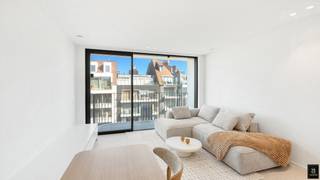 Luxueus en instapklaar nieuwbouwappartement met open zicht op het Van Bunnenplein, gelegen in het hart van Knokke. Door de terrassen aan de voor- en achterzijde kunt u de ganse dag genieten van de zon.<br />Indeling: inkomhal met apart gastentoilet en praktische berging met aansluiting voor wasmachine/droogkast. De lichtrijke leefruimte is afgewerkt met op maat ingemaakte kasten en met een open indeling gaat u door in de keuken. <br />Het appartement beschikt over vloerverwarming met warmtepomp en privatieve kelderberging. <br />Deze verkoop valt onder het BTW-stelsel.