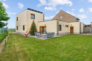 Recente woning voorzien van alle moderne comfort die, met uitzondering van enkele muren, volledig nieuw is opgetrokken en afgewerkt van 2018 - 2024. Hier is gekozen voor kwalitatieve materialen en de nieuwste technieken waardoor de woning zeer energiezuinig is (A-label).<br />De woning beschikt over 4 slaapkamers waarvan 2 op de gelijkvloerse verdieping, badkamer op de gelijkvloerse verdieping, hyper uitgeruste keuken, ruime woonkamer, berging, apart toilet, inpandige garage en fraai aangelegde tuin met bijgebouw en terras.<br /><br />U betreedt de woning via de centrale inkomhal met apart toilet. Hier heeft u toegang tot de vierde slaapkamer of bureauruimte. Ideaal voor zelfstandigen die klanten thuis wensen te ontvangen aangezien zij de privéruimtes niet moeten betreden. <br />Voorts bevindt zich de woonkamer met vooraan zicht op de weilanden en veel lichtinval. Van hieruit kan u de moderne keuken betreden die volledig is ingericht met Siemens/Miele toestellen (oven, microgolf, koffietoestel, stoomoven, vaatwasmachine, koelkast, diepvriezer, inductievuur). Deze is ook ingericht met veel opbergkasten en ruim kookeiland. Naast de keuken vindt u een extra bergruimte terug met toegang naar de kelder. Verder bevinden er zich op de gelijkvloerse verdieping een extra slaapkamer, alsook de zeer praktische badkamer. De badkamer is volledig betegeld en geïnstalleerd met inloopdouche, ligbad, toilet en dubbele lavabo. <br /><br />De eerste verdieping voorziet de woning van 2 extra ruime slaapkamers. Vanuit de master bedroom heeft u een prachtig uitzicht over de uitgestrekte weilanden. <br /><br />Bovendien beschikt de woning over een inpandige garage met automatische poort.<br /><br />Bijzonderheden:<br />- rustige locatie vlakbij de autosnelweg naar Antwerpen en Eindhoven, creche, kleuter -en lagere <br /> school, winkels etc.<br />- Energiezuinige woning met zonnepanelen en vloerverwarming (label A, E-peil 51)<br />- Komende 4 jaar vrijgesteld van betaling onroerende voorheffing<br />- Domotica<br />- Hoogwaardige afwerking