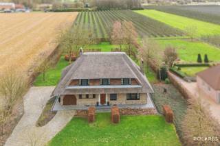 Aan de Heerbaan 62 in Kortenaken vindt u deze uitzonderlijke villa, waar rust, privacy en modern wooncomfort op harmonieuze wijze samenkomen.<br /><br />Gelegen op een indrukwekkend perceel van 25 are, biedt deze open bebouwing een zeldzaam gevoel van vrijheid, zowel binnen als buiten. De woning onderging in 2022-2023 een renovatie waarbij kosten noch moeite zijn gespaard: van een volledig vernieuwd dak en nieuwe raampartijen tot de installatie van zonnepanelen, wat resulteert in een energiezuinige woonervaring en een volledig conforme elektriciteit.<br /><br />Bij het betreden van de woning wordt u onmiddellijk verwelkomd door een royale inkomhal. De prachtige trap vormt hier het centrale pronkstuk en zet direct de toon voor de hoogwaardige afwerking die u in de rest van de villa terugvindt.<br /><br />De uiterst lichtrijke leefruimte is het hart van het huis; dankzij de grote raampartijen geniet u hier van een panoramisch zicht op de prachtig aangelegde, zuidgerichte tuin en het uitnodigende terras. De keuken is modern en volledig uitgerust en slim geschakeld met een praktische bureauruimte.<br /><br />De eerste verdieping ademt ruimte en comfort. Hier bevinden zich vier riante slaapkamers en een aparte dressing die aan al uw opbergwensen voldoet. De stijlvolle badkamer is een baken van rust, compleet ingericht met een dubbele lavabo, een ligbad en een moderne inloopdouche. Extra bergruimte is voorzien in de vorm van een handige bergzolder, en aangezien de woning volledig onderkelderd is, ontbreekt het u nooit aan plaats voor opslag of hobby’s.<br /><br />Buiten zet de luxe zich voort. De tuin is een waar paradijs waar u in alle privacy kunt ontspannen met een uniek zicht op de achtergelegen boomgaard. Er is verder een inpandige garage, terwijl de oprit parkeergelegenheid biedt aan meerdere wagens.<br /><br />Deze villa biedt een solide basis op een mooi domein, ideaal voor wie op zoek is naar een zorgeloze woning op een idyllische ligging met zicht op het groen.