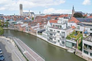 Op zoek naar een unieke woonst waar rust en stadsleven elkaar ontmoeten? Dit instapklaar appartement combineert een prachtige ligging aan het water met alle troeven van wonen in het centrum van Mechelen.<br /><br />Op de tweede verdieping vind je de inkomhal, een lichtrijke leefruimte met open keuken, een apart toilet, twee slaapkamers en een smaakvol ingerichte badkamer. Vanuit de leefruimte stap je rechtstreeks op een gezellig terras met prachtig zicht over de Dijle en naar de Grootbrug – de ideale plek om te ontspannen.<br /><br />De derde verdieping verrast met een ruime polyvalente ruimte die je volledig naar eigen wens kan inrichten: een extra slaapkamer, bureau of hobbyruimte, de keuze is aan jou. Van hieruit heb je toegang tot een groot tweede terras, eveneens aan de waterkant, waar je volop kan genieten van de buitenruimte en het unieke uitzicht.<br /><br />De combinatie van moderne afwerking, praktische indeling en de uitzonderlijke ligging maakt dit appartement een absolute topper. Je woont op wandelafstand van winkels, horeca en cultuur, terwijl je elke dag een vleugje vakantie ervaart aan de Dijle.<br /><br />Benieuwd om dit appartement zelf te ontdekken? Maak vandaag nog een afspraak voor een bezoek. Kan je niet wachten, dan kan je alvast een virtuele tour bekijken.
