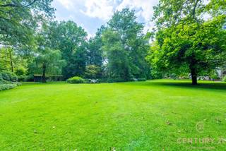 <p><strong>Karaktervol landhuis met prachtig aangelegde tuin en bijgebouw – uniek woonaanbod op toplocatie</strong></p>
<p>In een residentiële en rustige omgeving wacht dit uitzonderlijk goed onderhouden landhuis op haar nieuwe bewoners. Gelegen op een royaal dubbel perceel met een schitterend aangelegde en volgroeide tuin, biedt deze eigendom een unieke combinatie van charme, ruimte en veelzijdigheid.<br /><strong>Bovendien geniet u van een uitstekende bereikbaarheid: op slechts 25 minuten rijden van zowel Eindhoven (NL) als Antwerpen (BE)</strong> – een ideale ligging voor wie centraal, maar toch in alle rust wil wonen.</p>
<p>Via de ruime inkomhal met gastentoilet en aparte bureauruimte betreedt u de sfeervolle leefruimte. De gezellige open haard, de brede raampartijen en de naadloze overgang naar de eetkamer zorgen voor een warme, huiselijke sfeer met overal zicht op de prachtige tuin. De volledig uitgeruste keuken is aangenaam ruim en beschikt over een aansluitende berging.</p>
<p>Op de eerste verdieping bevinden zich vier volwaardige slaapkamers en drie badkamers. De masterbedroom beschikt over een eigen inloopdressing, een royale badkamer én een privé-sauna – een ware wellnessbeleving aan huis.</p>
<p>Een bijzonder pluspunt is het multifunctionele bijgebouw, dat bestaat uit een ruime garage met drie poorten en meer dan voldoende opbergruimte. De bovenverdieping van dit gebouw is ingericht als hobbyruimte met een gezellige bar, douche en apart toilet – ideaal als gastenverblijf, atelier, of als zelfstandige ruimte voor inwonende tieners of hulp. Deze verdieping is bereikbaar via een aparte buitentrap.</p>
<p>De tuin is werkelijk een parel: aangelegd als een rustgevend park met vijvers, wandelpaadjes en idyllische zithoekjes vormt het geheel een oase van groen en stilte.</p>
<p><strong>Kortom: een unieke kans voor wie op zoek is naar een karaktervol landhuis met veel ruimte, privacy, uitstekende bereikbaarheid en een uitzonderlijk mooie buitenomgeving.</strong></p>