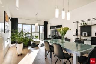 We vinden dit recent twee-slaapkamer-appartement (2013) langs de Rupel in Terhagen, op de site van de oude steenbakkerijen. Ook de architectuur van het gebouw en de hoge schoorsteen die bleef staan vormen een knipoog naar dit verleden. We hebben hier directe toegang tot het jaagpad. We bereiken het appartement op de eerste verdieping met de lift en we komen binnen langs een zeer mooie inkomhal met voldoende licht en ruimte. Langs een glazen deur betreden we de woonkamer die eveneens baadt in het licht dankzij grote raampartijen. De open keuken is perfect onderhouden en van alle comfort voorzien (combi-oven, koelkast met vriesvak, nieuwe vaatwas en nieuwe inductiekookplaat). De mooie Radson design-radiatoren en goed onderhouden parket zijn hier de blikvangers. Alle raamdecoratie en verlichting zijn trouwens aanwezig op het appartement. Vanuit de hal kunnen we verder nog naar een apart toilet met handenwasser, een ruime berging met aansluitingen voor was- en droogautomaat, twee slaapkamers (waarvan één met ingemaakte kasten) en de badkamer uitgerust met dubbel meubel en inloopdouche. Ook deze ruimtes hebben allemaal grote ramen. Het gebouw is voorzien van een afgesloten, gemeenschappelijke fietsenberging en de wagen kunnen we kwijt op de staanplaats onder het gebouw, vlakbij de lift. Deze zit mee in de huurprijs. Provisie vaste kosten : € 90,00 per maand. U kan een afspraak maken bij Daniel via mail (daniel@reds.be) of telefonisch (0475.25.30.64). Dat mag trouwens ook gerust 's avonds of in het weekend !