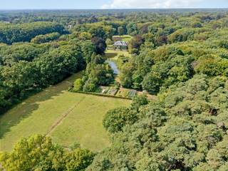 Te midden van een prachtig parklandschap, verscholen in rust en privacy, bevindt zich het uitzonderlijke domein Haezenveld te Kapellen. Oorspronkelijk gebouwd in 1938 door de grootvader van de huidige eigenaars, ademt dit eigendom een zeldzame combinatie van authenticiteit, elegantie en verfijnd wooncomfort.<br /><br />Het hart van het domein wordt gevormd door de prestigieuze villa. Een statige inkomhal leidt naar ruime ontvangstruimtes, waar hoogwaardige materialen zoals authentiek parket en sierlijke afwerkingen warmte en karakter brengen. De eetkamer met hoge plafonds en brede deuren, de prachtige bibliotheek met open haard en ingemaakte kasten, en het royale salon met meerdere zithoeken vormen samen een setting die zowel stijlvol als functioneel is.<br />Vanuit de villa geeft een overdekt terras zicht op de fraai aangelegde parktuin. Praktische voorzieningen zoals een keuken met aparte eethoek, wasplaats en kelders voor wijn en voorraad onderstrepen de doordachte indeling.<br />Op de eerste verdieping bevinden zich vier ruime slaapkamers, elk met verfijnde details en en-suite badkamers. Eén kamer beschikt bovendien over een open haard en balkon. Aanvullend zijn er drie kinderkamers en een hobbyruimte, eveneens bereikbaar via een buitentrap. De zolderverdieping biedt bijkomende kamers; logeerruimtes, personeelsvertrekken of bergruimtes.<br /><br />Naast de hoofdvilla maakt een gerenoveerde conciërgewoning (2019) (deels verhuurd) deel uit van het domein, aangevuld met drie garages, stallen en bergruimtes. <br /><br />Een afzonderlijk landhuis met tuin en afzonderlijke toegangsweg wordt optioneel aangeboden evenals bijkomende gronden, bossen en weiden. Het uitzonderlijke domein verruimd dan van ca. 10 ha naar ca. 15,3 ha.<br /><br />Een domein met uitstraling:<br />De omgeving van de villa is adembenemend. De vijver, Franse tuin, eeuwenoude bomen en uitgestrekte weilanden creëren een sfeer van rust en harmonie. <br />Het domein beschikt daarnaast over een te renoveren zwembad en tennisveld, evenals een moestuin met bijhorende kassen.<br /><br />De essentie van exclusiviteit:<br />Haezenveld is een uitzonderlijk eigendom dat klassieke elegantie koppelt aan hedendaags comfort. Het domein straalt discretie, grandeur en authenticiteit uit en behoort daarmee tot de meest bijzondere residenties van Noord-Antwerpen.<br /><br />Haezenveld is een levend kunstwerk; een schilderij waarin perspectieven en kleuren mee veranderen met de uren van de dag en de seizoenen. Paarden, schapen, zwanen, wilde eenden, reeën en talloze vogels maken deel uit van het decor. Muren die begroeid zijn met een meer dan tachtig jaar oude wilde wijnstok versterken de authenticiteit. <br />Enkel natuur, stilte, wooncomfort en discretie omarmen dit domein<br /><br />Buitengewone kenmerken:<br />Landgoed van ca. 100.000m² tot 153.000m²<br />Privatieve oprijlaan<br />Parking voor 10 wagens<br />Villa Haezenveld, Conciërgewoning (2019), garages (plaats voor 5 wagens), <br />Optioneel: Veldhuis (1971) met eigen toegangsweg en tuin<br />Park met vijver, eeuwenoude bomen, rododendrons, gazons en bospercelen<br />Vier weiden voor paarden en schapen<br />Moestuin met serre voor bloemen, groenten en fruit<br />Zwembad en tennisbaan (te renoveren)<br />Absolute rust en volledige privacy, zonder zichtbare buren of geluidsoverlast<br />Goede bereikbaarheid, open baar vervoer, scholen, winkels in de omgeving