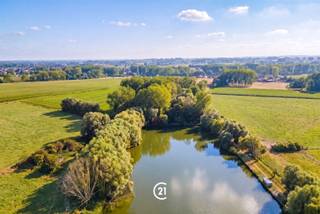Wonen waar elke ochtend als vakantie voelt.Twee prachtige bouwloten voor open bebouwing, gelegen in een rustige, groene straat, pal aan een sfeervolle vijver. Hier word je wakker met het zachte geluid van de natuur en zie je vanuit je slaapkamer de reigers en eenden voorbijtrekken.Geen drukte, geen haast. Wel ruimte, rust en een uitzicht dat elke dag opnieuw bijzonder is.Een plek waar kinderen vrij kunnen spelen, waar je ’s avonds geniet van de stilte en waar thuis écht thuiskomen betekent.Bouw hier niet zomaar een huis. Bouw een plek waar je elke dag gelukkig wordt.