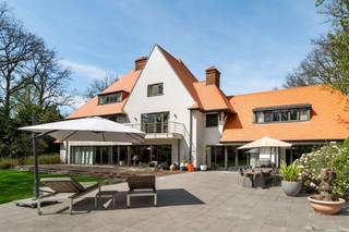 <p><span> </span></p><p><span>Deze ruime en kwalitatief afgewerkte villa is gelegen op een rustig en groen perceel en geeft comfort, privacy en snelle toegang naar alle snelwegen. De woning werd praktisch ingedeeld en biedt tal van mogelijkheden voor wonen, werken en ontspannen, zowel binnen als buiten. </span></p><p><span> </span></p><p><span>U betreedt de woning via de inkomhal met gastentoilet en directe toegang tot de bureauruimte/bibliotheek. Dit bureel is dus ideaal gelegen om mensen te ontvangen zonder dat men in de rest van de woning moet komen.  </span></p><p><span>De woonkamer is zeer ruim en vormt het centrale gedeelte van de woning. Deze leefruimte biedt een prachtig panoramisch zicht over de tuin. De living werd ingedeeld met een ruime zithoek bij de open haard en formele eetplaats. Aansluitend bevindt zich de leefkeuken met ontbijtzone,  welke praktisch werd ingericht en rechtstreeks verbonden is met de leefruimtes. Achter de keuken bevindt zich nog een tweede gastentoilet evenals een aparte audio- of homecinemaruimte, met daarboven een nog aparte studio. </span></p><p><span> </span></p><p><span>1e Verdieping</span></p><p><span>Via de centraal gelegen trap bereikt u de nachthal op de eerste verdieping. Hier bevindt zich een eerste ruime slaapkamer met aansluitende badkamer die gedeeld wordt met een achterliggende tweede slaapkamer. Verder is daarnaast een praktische wasplaats op deze verdieping. </span></p><p><span>De grote mastersuite beschikt over een ruime slaapkamer met aansluitende dressing (voorheen nog extra slaapkamer) en een royale badkamer voorzien van sauna en een ruime inloopdouche. Aan de voorzijde van de woning bevindt zich een studeerkamer welke ook deel uitmaakt van de mastersuite en welke eveneens dienst kan doen als een tweede dressing. Deze avond study is voorzien van een open haard.</span></p><p><span> </span></p><p><span>2e Verdieping</span></p><p><span>Ook de tweede verdieping werd volledig benut. Hier bevindt zich een bergzolder met ingemaakte kasten welke ideaal dienst doet als opbergruimte. Ook werd op de tweede verdieping een extra suite ingericht met aansluitende badkamer evenals een aparte studeer- of bibliotheekruimte. Daarnaast bevindt zich op deze verdieping nog een slaapkamer. </span></p><p><span> </span></p><p><span>Kelder</span></p><p><span>De woning is volledig onderkelderd. Hier bevinden zich diverse technische ruimtes en praktische bergruimtes. Tevens zijn er twee royale geklimatiseerde wijnkelders aanwezig. </span></p><p><span> </span></p><p><span>Garages en parkeren</span></p><p><span>Vooraan het perceel bevindt zich een ruime parkeerplaats met plaats voor circa 13 wagens evenals een carport naast de woning voor twee frequent gebruikte voertuigen, vlakbij de woning. </span></p><p><span>Achteraan het perceel, langs de oprit die aan de rand van het domein loopt, bevindt zich een afzonderlijke garage met plaats voor negen autos. </span></p><p><span> </span></p><p><span>Tuin en buitenruimtes</span></p><p><span>De tuin biedt u volledige privacy. Er is een ideaal gelegen zwembad dat recent gerenoveerd werd met ruime terrassen en aansluitend een poolhouse met leefruimte, douche, toilet en sauna. </span></p><p><span>Achteraan op het perceel bevindt zich een charmante chalet met twee slaapkamers, een keuken en een woonkamer, ideaal als gastenverblijf. </span></p><p><span> </span></p><p><span>Bijzonderheden</span></p><p><span>Deze exclusieve villa combineert royale woonruimtes met veel mogelijkheden tot ontspanning zoals zwembad, wellness en homecinema. De villa is zowel geschikt voor een groot gezin als voor een combinatie van wonen en werken. Dankzij onder meer de ruime parkeermogelijkheden, de volledig onderkelderde woning en het bijkomende gastenverblijf biedt dit eigendom een uitzonderlijk wooncomfort in een groene omgeving nabij het centrum van Brasschaat. </span></p><p><span> </span></p><p><span>Meer inlichtingen via ons kantoor.</span></p>