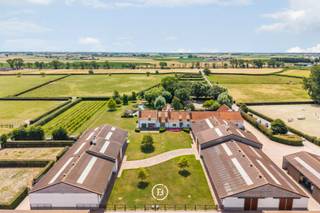 Een uitzonderlijk hippisch landgoed in het hart van de Polders. Te midden van het uitgestrekte polderlandschap van Middelkerke bevindt zich dit exclusieve domein van 25 ha. Een eigendom die zelden op de markt verschijnt en waar residentieel comfort, hoogwaardige hippische infrastructuur en landschappelijke rust harmonieus samenkomen. Het domein werd tussen 2007 en 2010 ontwikkeld met een duidelijke focus op paardenfokkerij en paardentraining.<br /><br />Het domein biedt een uitzonderlijk geheel aan hoogwaardige infrastructuur. Het trainingsgedeelte omvat 21 paardenboxen, verdeeld over twee afzonderlijke stallen, een overdekte piste, een ruime buitenpiste, een stapmolen voor zes paarden en meerdere paddocks. Het fokkerijgedeelte is minstens even compleet en beschikt over vijf ruime groepsstallen, vijf individuele boxen, vier veulenboxen, een laboratorium en twee opvoelboxen.<br />De uitgestrekte weilanden zijn omheind, voorzien van automatische drinksystemen en bieden optimale omstandigheden voor paarden. Alles is aanwezig voor een kwalitatieve uitbating als stoeterij, trainingscentrum of private paardenaccommodatie op topniveau.<br /><br />De strategische ligging vormt een bijkomende troef. Op slechts enkele minuten van de Belgische kust, met een vlotte verbinding naar de E40, is dit een ideale uitvalsbasis voor zowel professionele ruiters als fokkers.<br /><br />Het residentiële gedeelte omvat een bewoonbare oppervlakte van 624 m², verdeeld over een stijlvolle villa en een afzonderlijke gastenwoning. Daarnaast werden bijkomende woongelegenheden voorzien in de vorm van woningen, appartementen en studio's, ideaal voor trainers, fokkers, personeel of gasten die op het domein verblijven.<br /><br />Dit prestigieuze landgoed biedt een uitzonderlijke opportuniteit voor wie op zoek is naar een volledig uitgeruste hippische eigendom gecombineerd met een hoogwaardige residentiële invulling in een discrete en groene omgeving aan de Belgische kust.