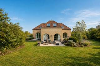 Op een van de meest gegeerde locaties aan de Belgische kust, verscholen in de prestigieuze villawijk Witte Burg, ligt deze uitzonderlijke eigendom. Omringd door duinen, eeuwenoude bomen en een ongekende rust geniet deze villa van een zeldzame combinatie van absolute privacy, natuur en exclusiviteit en dit op wandelafstand van dorpswinkels. <br /><br />Gelegen op een prachtig perceel van 1.755 m² vormt deze karaktervolle villa een unieke plek waar binnen en buiten naadloos in elkaar overvloeien. De woning, gebouwd in 1987, beschikt over een bewoonbare oppervlakte van ongeveer 199 m² en biedt bovendien interessante uitbreidingsmogelijkheden, waardoor ze zich moeiteloos laat aanpassen aan de woonwensen van morgen.<br /><br />De royale inkomhal zet meteen de toon. Lichtrijke leefruimtes met grote raampartijen kijken uit op het omliggende groen en baden de woning de hele dag in natuurlijk licht. Een gezellige tweede salon creëert een intieme plek om te ontspannen, terwijl de afzonderlijke keuken alle mogelijkheden biedt voor een eigentijdse invulling.<br /><br />Op het gelijkvloers bevindt zich tevens een stijlvolle bureauruimte met uitzicht op de tuin en een comfortabele master suite met een recent vernieuwde badkamer en apart toilet. Op de verdieping bevinden zich drie ruime slaapkamers, elk met een eigen badkamer, waardoor familie en gasten in alle comfort en privacy kunnen verblijven.<br /><br />Ook buiten straalt dit eigendom een bijzondere sereniteit uit. De prachtig aangelegde tuin vormt een discreet verlengstuk van het omliggende duinenlandschap en biedt een uitzonderlijk gevoel van vrijheid.<br /><br />Een dubbele garage, een ruime oprit en een praktische ondergrondse wasplaats vervolledigen het comfort van deze villa.<br /><br />Eigendommen op deze locatie worden slechts zelden aangeboden. Deze villa biedt een unieke kans om te wonen op een van de meest exclusieve adressen van Oostduinkerke, waar natuur, discretie en een uitzonderlijke woonkwaliteit samenkomen.<br /><br />Kenmerken<br /><br />Prestigieuze ligging in de residentiële villawijk Witte Burg<br /><br />Perceel van 1.755 m²<br /><br />Bewoonbare oppervlakte ca. 199 m²<br /><br />Mogelijkheid tot uitbreiding<br /><br />4 slaapkamers<br /><br />4 badkamers<br /><br />Bureauruimte<br /><br />Twee leefruimtes<br /><br />Dubbele garage<br /><br />Ondergrondse wasplaats<br /><br />Ruime oprit<br /><br />Terras en prachtig aangelegde tuin<br /><br />P-score: A<br /><br />G-score: A