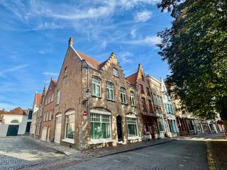 Unieke HERENWONING met grote GARAGE, STADSTERRAS, 2 slaapkamers en 2 badkamers in hartje Brugge
Centraal gelegen, nabij de Spinolarei, het Jan Van Eyckplein, de Burg en de Markt, bevindt zich deze karaktervolle herenwoning. De woning werd recent gerenoveerd met oog voor kwaliteit en detail, waarbij authentieke elementen en hedendaags comfort harmonieus samengaan. Warme houten balken, parketvloeren en stijlvolle materiaalkeuzes zorgen voor een bijzonder sfeervol geheel.
Op het gelijkvloers bevindt zich een royale inkomhal met gastentoilet, een slaapkamer/bureauruimte met aansluitende douchekamer, een ruime garage met maatkasten, een praktische, volledig ingerichte wasplaats met kasten en een kelder.
De eerste verdieping vormt het hart van de woning. De lichtrijke leefruimte is voorzien van een mooie parketvloer en een authentieke open houthaard. De volledig ingerichte open keuken sluit hier naadloos op aan en is uitgerust met een natuurstenen werkblad en kwalitatieve inbouwtoestellen. Vanuit de keuken is er rechtstreeks toegang tot het aangename stadsterras.
De tweede verdieping omvat een ruime masterbedroom met maatkasten en een luxueuze badkamer met een dubbel lavabomeubel, ligbad, douche en toilet.
Met een EPC van 116 kWh/m² (E-peil 66), conforme elektrische installatie combineert deze woning karakter met hedendaags wooncomfort.
Een stijlvolle stadswoning met een uitzonderlijke combinatie van authenticiteit, comfort, buitenruimte en garage, midden in het historische hart van Brugge.