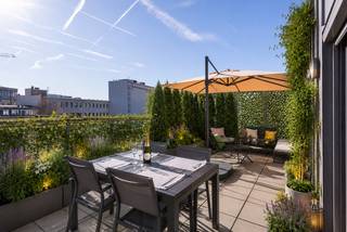 Deze instapklare penthouse is gelegen in de Lange Sint-Annastraat, een karaktervolle straat in het hart van Antwerpen, op het kruispunt van het Eilandje, de universiteitswijk en het historische centrum. Stijlvolle winkels, kwalitatieve horeca en culturele hotspots bevinden zich op wandelafstand, net als de Meir, Groenplaats en Grote Markt. Dankzij deze centrale ligging geniet u van het bruisende stadsleven, terwijl u bovenaan het gebouw in alle rust thuiskomt. Zowel openbaar vervoer als belangrijke invalswegen zijn vlot bereikbaar.<br /><br />Het appartement bevindt zich op de bovenste verdieping van een recente en verzorgde residentie. De lichtrijke leefruimte vormt het hart van het appartement en geeft via grote raampartijen toegang tot twee ruime zonneterrassen aan weerszijden. Dit zorgt de hele dag door voor overvloedig natuurlijk licht en een aangenaam panoramisch uitzicht over de stad. Aansluitend aan de leefruimte bevindt zich een aparte bureauruimte, ideaal als thuiswerkplek of in te richten als derde slaapkamer.<br /><br />De keuken is volledig uitgerust met kwalitatieve toestellen en een ruim werkblad, perfect voor wie graag kookt en gasten ontvangt. Verder beschikt het appartement over twee ruime slaapkamers, een modern afgewerkte badkamer met ligbad, inloopdouche en dubbel lavabomeubel, een apart gastentoilet en een praktische (was) berging. <br />Een privatieve kelderberging en gemeenschappelijke fietsenberging zijn inbegrepen. De aankoop van een ondergrondse autostaanplaats is mogelijk.