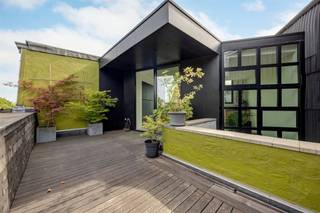 <p><span>Achter deze prachtige eclectische gevel gaat een woning schuil die je onmogelijk vanop straat kunt inschatten. Wat ooit een klassieke stadswoning was, groeide door een doordachte renovatie uit tot een unieke architecturale thuis waar licht, ruimte en beleving centraal staan. Dankzij de speelse split-levelindeling, de centrale patio, het royale dakterras en de indrukwekkende leefkeuken voelt elke verdieping anders aan, terwijl het geheel één harmonieus verhaal vormt. Een zeldzame woning voor wie houdt van karakter, design en wonen met</span><span> </span><span>een eigen identiteit.</span></p><p><span> </span></p><p><span>Architectuur die je stap voor stap ontdekt</span><span><br />Van zodra je de dubbele voordeur opent, merk je dat dit geen doorsnee stadswoning is. De brede inkomhal baadt in het daglicht dankzij de hoge ramen aan beide zijden van de woning. De tweede inkom achteraan is bijzonder praktisch en de ruimte kan perfect multifunctioneel ingezet worden, als werkruimte/ fietsenberging/ atelier,… je vindt er ook de technische ruimte terwijl een aparte wasruimte en de kelder het dagelijkse comfort compleet maken.<br />Wat deze woning echt bijzonder maakt, is de manier waarop de verschillende niveaus met elkaar verbonden zijn. Geen lange donkere gangen of afgesloten verdiepingen, maar een speelse circulatie waarbij je telkens nieuwe zichten krijgt op de woning. De centrale patio brengt het daglicht tot diep in het huis en zorgt ervoor dat de verschillende leefruimten voortdurend met elkaar in verbinding staan.<br />De eerste verdieping is volledig ingericht als slaapverdieping. De master bedroom vormt een rustige privésuite met een ruime dressing en een ensuite badkamer. Daarnaast zijn er nog twee slaapkamers met zicht op het groen en een tweede douchekamer.</span></p><p><span> </span></p><p><span>Leven op verschillende niveaus</span></p><p><span>De tweede verdieping vormt een heerlijke overgang. De lichte zitkamer kijkt uit op het groen en sluit aan op een gezellige tv-hoek. Daarnaast bevindt zich een bureau op maat met ingemaakte kasten. Centraal ligt een patio die het natuurlijke licht diep de woning in trekt en een bijzonder gevoel van openheid creëert.<br /><br /></span></p><p><span>Een keuken waar het leven zich afspeelt</span></p><p><span>Helemaal boven bevindt zich de leefkeuken van ongeveer 30 m². De maatwerkkeuken met natuurstenen werkblad, Lacanche-gasfornuis, Quooker, grote koelkast en veel kastruimte vormt het kloppende hart van de woning. Via de grote schuiframen stap je naar het oostgerichte dakterras van 17 m² met zicht op de boomkruinen.</span></p><p><span> </span></p><p><span>Een buurt waar je graag thuiskomt</span><span><br />De Stanleystraat ligt op de grens van Oud-Berchem, Zurenborg en het Groen Kwartier. 's Morgens wandel je naar Polly voor een specialty coffee of spreek je af bij Café Service op de hoek van de straat. Station Antwerpen-Berchem, winkels, restaurants en openbaar vervoer liggen allemaal op wandelafstand.</span></p><p><span> </span></p>