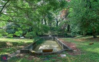 Deze neoclassicistische herenwoning anno 1868 met dubbelhuisopstand, de voormalige brouwerswoning van de brouwerij Du Bois-Haems, is gelegen in hartje Lebbeke, temidden van de driehoek Brussel-Gent-Antwerpen. Het interieur bevat talloze decoratieve elementen, waaronder een salon in Lodewijk XVI-stijl, mozaïekvloeren, stucplafonds, marmeren schouwen,...Dit pareltje heeft een parktuin van 59 are 51 ca met vijver, Lourdesgrot, antiek zwembad en talrijke imposante bomen waaronder een bruine beuk en linden. Deze indrukwekkende woning heeft een zeer ruime leefruimte (94 m²) met 3 schouwen en een leefkeuken (51 m²) met oa een AGA-fornuis, op de verdieping zijn er onder andere 7 slaapkamers en 2 badkamers. Naast de 2 garages, de wijnkelder, de paardenstallen en een gastenverblijf is er een inrijpoort met automatische poort en een met kasseien nieuw aangelegde binnenkoer. Alle technieken werden recentelijk vernieuwd (centrale verwarming op aardgas, riolering, elektriciteit), alsook de leefkeuken en de 2 badkamers met Old English douche,ligbad en wastafels. Deze woning is beschermd als monument, waardoor U kan aankopen onder het gunstig stelsel van 1% registratiekosten op voorwaarde dat de woning als gezinswoning wordt aangewend én dat er investeringen worden gedaan aan het pand. Zoniet blijft de 5%-regel gelden. Het bekomen fiscaal voordeel wordt aanzien als een fictieve subsidie, waarbij de koper binnen de vijf jaar na zijn aankoop 6% van de aankoopprijs dient te investeren in onderhouds- of renovatiewerken van het pand. Zodoende zou de nieuwe eigenaar dus 7% van de aankoopprijs betalen, zijnde 1% registratierechten en 6% aan investeringen. U kan ook daarnaast ook genieten van restauratie-en of renovatiepremies. Meer info op: https://www.onroerenderfgoed.be/nl/premies/ EPC: 432 kWh/m²/j. en UC:2070674-RES-2