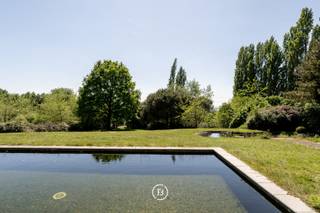 Op een uitzonderlijke ligging op de Scherpenberg, midden in het groen en met volledige privacy, bevindt zich deze karaktervolle villa op een perceel van 12.203 m². Met een bewoonbare oppervlakte van maar liefst 503 m², biedt deze woning een zeldzame combinatie van ruimte, licht en architecturale charme. De eigendom vereist een verdere renovatie, maar beschikt reeds over belangrijke vernieuwingen: een recent geplaatst rieten dak, een volledig nieuwe keuken, vloerverwarming en zonnepanelen.<br /><br />De imposante inkomhal, afgewerkt met marmeren vloeren en een massief eiken trap, vormt het hart van de woning. Rechts leidt een open doorgang naar de eerste leefruimte met zicht op tuin en terras, met daaraan verbonden een vestiaire en gastentoilet. Verder op het gelijkvloers bevinden zich een kinderkamer of bureauruimte, een badkamer en een extra slaapkamer. Aan de linkerzijde van de inkom ligt de nieuwe keuken, naadloos verbonden met de eetplaats en een tweede, lichtrijke leefruimte met een charmante rondboogerker en uitzicht op de tuin. Een centrale houthaard scheidt eetplaats en salon op sfeervolle wijze. Zowel de keuken als eetruimte geven uit op het ruime terras en het zwembad, met prachtig zicht op de tuin.<br /><br />Grenzend aan de eetplaats bevindt zich een tweede inkomhal met een toilet en een trap naar de au pair kamer. Via de naastgelegen berging en wasplaats is er toegang tot de voortuin en tot de kelderverdieping met wijnkelder, berging en dubbele garage.<br /><br />Op de verdieping bevinden zich drie ruime slaapkamers, waaronder een kamer met aparte bureauruimte en een andere met ensuite badkamer met ligbad, douche, dubbele wastafel en een apart toilet. Twee slaapkamers bieden toegang tot een breed balkon met uitzicht over de tuin. De nachthal is voorzien van ingemaakte kasten.<br /><br />Dankzij de verschillende ingangen, de aparte leefdelen en het royale volume is deze eigendom perfect inzetbaar als kangoeroewoning of voor de uitoefening van een vrij beroep. De woning deed jarenlang dienst als woonst en atelier van een gerenommeerd kunstenaar — het karakter en de potentie zijn dan ook overduidelijk aanwezig voor wie op zoek is naar een unieke woonplek met ziel en toekomst.