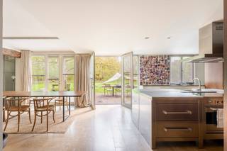 <p>Deze prachtig gerenoveerde 18e-eeuwse hoeve, gekend als de <strong>Calsterhoeve</strong>, is een unieke eigendom waar charme en hedendaags comfort samenkomen. Gelegen op een uitzonderlijk perceel van maar liefst 18.486 m² en volledig omringd door bos en groen, geniet u hier van absolute rust en privacy.</p>
<p>Via een oprijlaan bereikt u deze karaktervolle woning, die met bijzonder veel zorg en respect voor haar historisch karakter werd gerenoveerd. Authentieke elementen werden behouden en harmonieus gecombineerd met moderne ingrepen, zoals grote glazen gevels die zorgen voor een overvloed aan natuurlijk licht en een uitgesproken ruimtelijk gevoel.</p>
<p>Bij het betreden van de woning komt u in een ruime centrale inkomhal. Vanuit de hal heeft u toegang tot de ruime en lichtrijke leefkeuken, die prachtig zicht biedt op de omliggende tuin. Daarnaast bereikt u via de hal de eetplaats, waarvanuit u ook naar de keuken toe kunt. <span>Vanuit de eetplaats heeft u toegang tot een aangename grote leefruimte, die met oog voor authenticiteit werd omgevormd tot een indrukwekkende ruimte, waar u geniet van een prachtig zicht op het omliggende groen dankzij de grote raampartijen. </span></p>
<p>De open keuken is uitgerust met een inox kookeiland en aangevuld met warme houten kasten. Vanuit de keuken heeft u directe toegang tot het terras.</p>
<p>De woning beschikt over vier slaapkamers, 2 badkamers en een multifunctionele ruimte met aparte ingang, ideaal als praktijkruimte, hobbyruimte of voor een zelfstandige activiteit. Daarnaast zijn er drie toiletten aanwezig.</p>
<p>Op het eerste verdiep omvat de ene zijde een ruime slaapkamer met een en suite dressing en een en suite badkamer, voorzien van ligbad, inloopdouche en dubbele wastafel, evenals een apart toilet. Deze slaapkamer wordt extra gekenmerkt door een grote raampartij met toegang tot een charmant privéterras. De andere zijde bestaat uit meerdere slaapkamers, een tweede badkamer met inloopdouche, bad en wastafel, en een praktische was- en droogruimte.</p>
<p>Buiten geniet u van een prachtig aangelegde tuin met tuinhuis en uitgestrekte groenzones die tal van invullingen mogelijk maken. Dankzij de aanwezigheid van zonnepanelen wordt bovendien ingezet op energiezuinig en toekomstgericht wonen.</p>
<p><strong>De Calsterhoeve</strong>, de oudste hoeve in alle omstreken, is de ideale eigendom voor wie op zoek is naar ruimte, rust en karakter, gecombineerd met modern wooncomfort in een unieke, groene setting.</p>