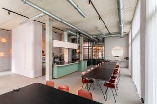 <p>Deze veelzijdige handelsruimte van ca 147 m² werd in 2019 afgewerkt en is gelegen op een werkelijke toplocatie pal in het Groen Kwartier. Deze site, een voormalig militair hospitaal, werd omgevormd tot een sublieme mix van wonen &amp; werken met een bestaande ziel in combinatie met veel groen en minimalistische nieuwbouw. Ondertussen één van de meest gegeerde wijken in Antwerpen, dankzij buren zoals August, PAKT en Broodnatie. <br /><br />Dankzij de grote raampartijen en hoge plafonds is er de hele dag door een prachtige natuurlijke lichtinval. Bovendien geen gebrek aan visibiliteit dankzij de hoekligging met open zicht op een groen aangelegd pleintje.</p>
<p>De polyvalente ruimte werd voorzien van een doorlopende gietvloer in terrazzolook, prachtig gedetailleerd en toch een neutrale basis.</p>
<p>De grote open ruimte - recht op recht - is ingericht met een industriële open keuken met kookeiland (Induchef). Ook hier zorgen de details in messing en muntgroen schrijnwerk voor een luxueuze &amp; huiselijke indruk.</p>
<p>Doordachte materiaalkeuzes zorgen ervoor dat deze open ruimte perfect kan afgescheiden worden van de huidige afwasruimte &amp; bereidingskeuken dankzij het gebruik van staal en flutesglas.</p>
<p>Deze aparte, achteraan gelegen keukenruimtes kunnen ook polyvalent ingericht worden als kantoor, stockage etc en grenzen aan een privatieve patio van ca 46 m² met tweede (dienst)toegang en rechtstreekse lift naar de ondergrondse garage. In deze patio werd ook reeds een water- en elektriciteitsaansluiting voorzien.</p>
<p>Tot slot werden 2 aparte sanitaire ruimtes voorzien aan de inkom. Werkelijk een staaltje pure luxe met als eyecatcher een marmer lavabomeubel naar een eigen ontwerp van de eigenares.</p>
<p>Momenteel in gebruik als evenementenruimte voor privéfeesten. Maar dankzij de polyvalente indeling leent deze handelsruimte zich ook ideaal als standingvolle praktijk, kunstgalerij, Pilates studio, kantoorruimte of showroom. <br />Thans vergund als commerciële ruimte.<br /><br />Een ruime autostaanplaats in de ondergrondse garage kan worden aangekocht aan 40.000 Euro, exclusief registratiebelasting.</p>