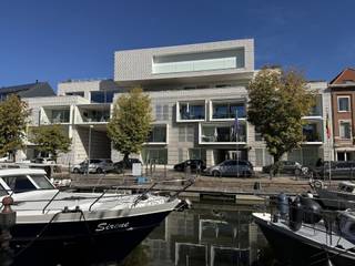 Wonen aan het water!Via de centrale inkomhal komen we uit in de living met open keuken, terras en berging. Verder is er een WC, badkamer met douche en 2 slaapkamers welke uitgeven op het 2de terras.Verder beschikt het appartement over een ondergrondse autostaanplaats met laadpaal alsook een kelderberging.Gelegen in centrum Mechelen, nabij Vismarkt/Lamot site.