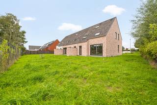 In het residentiële nieuwbouwproject ‘Reynaert’ in Zwevezele wordt deze duurzame halfopen woning gerealiseerd in een landelijke bouwstijl. De woning ligt op een perceel van 353 m² en beschikt over een zuidgerichte tuin. Op de eigen oprit is plaats voor de wagen en er is de mogelijkheid om een carport te voorzien. Via de inkomhal kom je binnen in de open leefruimte, die naadloos aansluit op de volledig uitgeruste keuken met keukeneiland. Vanuit de keuken heb je rechtstreeks toegang tot de praktische berging/wasplaats, wat zorgt voor een doordachte indeling en extra dagelijks comfort. Op de eerste verdieping bevinden zich drie slaapkamers en een ruime badkamer met dubbele wastafel, douche en bad. Een vaste trap leidt naar de open zolderruimte, waar de mogelijkheid bestaat om een extra kamer in te richten. Na aankoop wordt het interieur verder afgewerkt volgens jouw wensen en smaak. Zo geef je de woning een persoonlijke invulling en creëer je een thuis die helemaal bij jou past. Ook op het vlak van energiezuinigheid is deze woning klaar voor de toekomst. De geothermische warmtepomp in combinatie met vloerverwarming zorgt voor een aangename verwarming in de winter en energiezuinige passieve koeling tijdens de zomer.<br /><br />De vermelde prijs omvat zowel de grond als een volledig afgewerkte, instapklare woning. Ook de voorziene afwerkingen en voorzieningen zijn inbegrepen, waaronder een budget voor keuken en badkamer inclusief sanitair, warmtepomp, zonnepanelen, vloerverwarming, keuringen, terras, oprit, afsluiting en grasaanleg. Enkel de wettelijke kosten zijn nog niet inbegrepen. Bekijk de transparante ALL-IN prijs voor een volledig afgewerkte en instapklare woning, inclusief notariskosten, aansluitkosten, verkooprecht en btw, op onze website: www.dumobil.be/nl/woonprojecten/projecten/zwevezele-reynaert Of vraag vrijblijvend meer informatie aan onze bouwadviseur Sam Borrey via sam@dumobil.be of 0483 210 133.