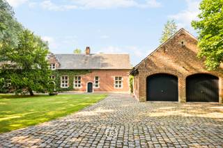 Hof ter Saele est situé sur un domaine historique de 52 ares qui faisait autrefois partie des biens féodaux de l’abbaye d’Affligem, avec une histoire de destruction et de reconstruction en 1643. La propriété est accessible par une allée de tilleuls majestueuse, avec un verger attenant d’arbres fruitiers. La maison dégage beaucoup de caractère grâce à des éléments authentiques tels que de hauts plafonds, des sols en pierre naturelle, des structures en poutres de chêne et des cheminées décoratives.<br /><br />La maison offre 488 m² habitables avec de beaux volumes.<br /><br />Au rez-de-chaussée, vous entrez par un hall d’entrée spacieux avec vestiaire et toilette invités. L’aile gauche donne accès à un bureau ou chambre d’amis pouvant servir de chambre supplémentaire, ainsi qu’à une buanderie avec raccordements. L’aile droite s’ouvre sur un séjour chaleureux avec cheminée, relié à la salle à manger et à la cuisine rénovée avec coin petit-déjeuner.<br /><br />À l’étage, un vaste hall de nuit avec placards intégrés et espaces de rangement. Trois chambres, dont une suite parentale avec salle de bain attenante avec baignoire et douche. Les deux autres chambres partagent une salle de bain.<br /><br />La propriété comprend un bâtiment annexe utilisé comme garage avec deux portes d’accès, espace pour deux voitures et rangement. Il dispose aussi d’un grenier pour stockage supplémentaire. Un second petit bâtiment sert de cabane de jardin. La maison est idéalement située sur l’axe Bruxelles–Gand, proche des commerces et écoles. Le jardin orienté plein sud, clôturé et sans vis-à-vis, offre calme et intimité.