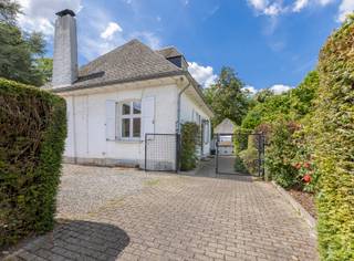 <p><strong>Karaktervolle villa op rustige, residentiële ligging in Schepdaal</strong></p>
<p>In een aangename en rustige straat, vlakbij belangrijke invalswegen, treffen we deze statige villa op een perceel van 10 are. De woning dateert uit 1965 en biedt een solide basis voor wie op zoek is naar ruimte, charme en een rustige, groene omgeving.</p>
<p>De villa bevindt zich in een degelijke staat, al is een <strong>energetische renovatie</strong> vereist. Zo zijn onder meer de dakconstructie, verwarmingsketel en enkele houten ramen met enkel glas toe aan vernieuwing.</p>
<p><strong>Indeling</strong><br />Via de ruime inkomhal bereik je de grote en lichtrijke leefruimte met eetplaats, salon met houtcassette en een aangename bureauhoek. De gesloten keuken werd in 2017 vernieuwd en biedt alle comfort.<br />De mooie houten trap brengt je naar de eerste verdieping met afzonderlijk toilet, drie slaapkamers (12,5m², 14m² en 15m²) waarvan enkele met ingebouwde kasten, een vernieuwde douchekamer (3 m²) en een ruime badkamer.<br />De zolder is bereikbaar via een uittrekbare trap en kan gebruikt worden als stockagezolder.</p>
<p>De kelderverdieping is bijzonder praktisch ingedeeld en omvat een inpandige garage (ca. 22 m²), een wijn-/proviandkelder (9 m²) en een royale wasplaats (25 m²).</p>
<p>De leefruimte sluit naadloos aan op het zonnige terras en de achterliggende tuin met volgroeide bomen. Van hieruit heb je eveneens toegang tot het afzonderlijke garagegebouw, die ook kan worden ingericht als atelier, bergplaats of poolhouse.</p>
<p><strong>EPC:</strong> 877 kWh/m²/jaar – Klasse F<br /><strong>Elektriciteit:</strong> niet conform<br /><strong>Asbestattest:</strong> niet asbestveilig</p>
<p>Deze karaktervolle villa vormt een uitstekende opportuniteit voor wie wil investeren in een ruime woning op een toplocatie in Schepdaal, met alle troeven om er een prachtige, toekomstgerichte thuis van te maken.</p>