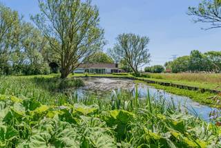 <p>Op een uitzonderlijke locatie in het charmante Lissewege, op slechts enkele minuten van het strand en de Belgische kust, bevindt zich deze unieke villa op een prachtig domein van ca. 10.000 m². Hier geniet u van absolute rust, privacy en fenomenale verzichten over de omliggende natuur.</p>
<p>De woning beschikt over een inkomhal met apart gastentoilet en een centrale gang die toegang biedt tot de slaapkamer, badkamer en keuken. De lichtrijke leefruimte met open keuken vormt het hart van de woning en biedt een prachtig zicht op het omliggende groen. Zowel aan de voor- als achterzijde bevindt zich een veranda, waardoor u het hele jaar door optimaal kunt genieten van de unieke omgeving.</p>
<p>Via het afgesloten terras bereikt u het bijgebouw, uitgerust met een tweede keuken en een authentieke wijnkelder. Ideaal als hobbyruimte, ontvangstruimte of voor wie graag gasten ontvangt. Daarnaast beschikt de woning over een inpandige garage met rechtstreekse toegang tot de woning.</p>
<p>Op de verdieping bevindt zich een ruime open ruimte met bijkomende bergruimte, die perfect kan worden ingericht als tweede slaapkamer, bureau of polyvalente ruimte.</p>
<p>Buiten wacht een uitzonderlijk domein met een sfeervolle vijver, volwassen bomen en een ongeëvenaard gevoel van ruimte. Een unieke eigendom voor wie op zoek is naar exclusief wonen midden in het groen, met de kust en het strand binnen handbereik.</p>
<p>Een zeldzame kans op een toplocatie waar rust, natuur en wooncomfort perfect samenkomen.</p>