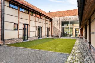 In het hart van het gegeerde Wimmertingen, op de Luikersteenweg 512, bevindt zich het uitzonderlijke en beschermd pand “Hoeve De Klok” – een uniek gesloten hoevecomplex dat authenticiteit en hedendaags comfort op sublieme wijze combineert.<br />Aan de straatzijde bevindt zich het statige poortgebouw met een ruim te renoveren woonhuis, ideaal als toekomstig kantoor, praktijk of woongedeelte. Dankzij de centrale ligging, de uitstekende bereikbaarheid en de nabijheid van een ruime parking is dit een uitgelezen locatie voor wie wonen en werken wil combineren. Voor dit gedeelte is bovendien een apart huisnummer mogelijk.<br />Georiënteerd op de ruime tuin vind je de voormalige vakwerkschuren, die met veel zorg voor detail en respect voor het erfgoed werden omgevormd tot een moderne, instapklare woning. <br />De renovatie gebeurde met oog voor energie-efficiëntie en comfort, waarbij hedendaagse technieken en hoogwaardige materialen werden geïntegreerd zonder afbreuk te doen aan het authentieke karakter van het gebouw.<br />De woning beschikt over vloerverwarming in combinatie met een lucht-water warmtepomp, een ventilatiesysteem type C en een geavanceerd domoticasysteem. Daarnaast werd er gedacht aan modern wooncomfort met een laadpaal voor elektrische wagens, automatische screens aan de voorgevel, en een gezellige houthaard als sfeervol middelpunt van de leefruimte.<br />Verder is het pand uitgerust met regenwaterrecuperatie, en een centraal audiosysteem dat in de hele woning geïntegreerd is. De volledig uitgeruste keuken met kwalitatieve inbouwtoestellen vervolledigt het geheel en maakt deze woning meteen instapklaar voor wie comfort en authenticiteit wil combineren.<br />De bovenverdieping telt momenteel 2 ruime slaapkamers, maar kan eenvoudig worden uitgebreid of heringedeeld volgens eigen wensen. De slimme inrichting met lichttracks, programmeerbare verlichting, onzichtbare vloerkanalen en talrijke data-aansluitpunten maakt dit pand bijzonder polyvalent.<br />De gebouwen zijn gegroepeerd rond een sfeervolle zuidwestgerichte binnenruimte die door de ommuring een aangenaam microklimaat creëert – ideaal voor een intiem terras of binnentuin. Daarachter strekt zich een ruime, rustige tuin uit die aansluit op een natuurgebied: een perfecte plek om tot rust te komen of om te vertrekken voor ontspannende wandelingen in het groen. Bron bewoonbare oppervlakte: EPC.<br /><br />Buitengewone kenmerken: <br />- Vloerverwarming<br />- Lucht-water warmtepomp<br />- Ventilatiesysteem type C<br />- Domoticasysteem<br />- Laadpaal<br />- Automatische screens aan de voorgevel<br />- Branddetectiesysteem met voorbereiding inbraakdetectie<br />- Centraal audiosysteem<br />- Te renoveren extra woning +- 200m2