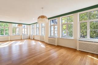 <p>In de levendige Sint-Andrieswijk, tussen het Zuid en het historische centrum van Antwerpen, bevindt zich dit bijzonder tweeslaapkamerappartement van ca 126 m². De hoekligging, royale raampartijen en doordachte renovatie zorgen voor een interieur dat meteen opvalt door zijn licht, ruimte en eigen karakter.<span></span></p>
<p>De leefruimte vormt zonder twijfel het hart van het appartement. Dankzij de vele ramen langs verschillende zijden valt het daglicht rijkelijk binnen en ontstaat er een aangename openheid doorheen de ruimte. De warme houten vloer vormt een rustige basis voor de uitgesproken keuken, waar gedurfde kleuren en organische lijnen voor een speels architecturaal accent zorgen. Het afgeronde werkblad vloeit bijna als een meubelstuk door in de leefruimte en creëert tegelijk een leuke plek om te zitten of te ontbijten. De keuken is volledig uitgerust met de nodige inbouwtoestellen waaronder retro SMEG koelkast en diepvriezer, combi-oven, vaatwasser en kookplaat.</p>
<p>Ook in de slaapvertrekken werd dezelfde aandacht aan materiaal en vorm doorgetrokken. De hoofdslaapkamer beschikt over een grote wand met ingemaakte kasten en een eigen badkamer met ligbad, douche, toilet en lavabomeubel. De tweede ruime slaapkamer geniet eveneens van een ensuite badkamer met douche en lavabo. Zachte, minerale afwerkingen, afgeronde vormen en zwarte accenten geven beide badkamers een rustige maar uitgesproken uitstraling.</p>
<p>De indeling is bovendien bijzonder comfortabel: beide slaapkamers beschikken over hun eigen badkamer en liggen afgescheiden van de leefruimte, waardoor wonen en slapen mooi van elkaar worden gescheiden.</p>
<p>Tot slot beschikt het appartement over een afzonderlijk gastentoilet en een ruime berging met aansluiting voor wasmachine en droogkast. Een privatieve kelderberging is eveneens inbegrepen.</p>
<p>Een inpandige autostaanplaats wordt mee aangeboden voor 65.000 Euro.</p>