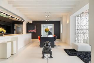 Au cœur de Diest se trouve ce loft d’exception, conçu par PCp Architects. Son architecture se distingue par une esthétique minimaliste en noir et blanc, des lignes épurées et un travail sur mesure soigné. Les rangements intégrés et les techniques dissimulées renforcent le caractère épuré de l’intérieur. Le loft offre 285 m² de surface habitable, complétés par une terrasse sur le toit d’environ 100 m² et une vue panoramique sur la ville.<br /><br />L’espace de vie constitue le cœur du loft et associe de généreuses proportions, de grandes baies vitrées et une cheminée ouverte. La cuisine entièrement équipée comprend notamment un wok intégré. Les appareils électroménagers peuvent être dissimulés derrière un volet à commande électrique, préservant ainsi une esthétique parfaitement épurée.<br /><br />Le même niveau comprend deux chambres, chacune avec sa propre salle de bains, ainsi que de nombreux rangements intégrés.<br /><br />L’étage supérieur est dédié à la vie extérieure. De grandes baies coulissantes relient directement l’intérieur à la terrasse sur le toit. Un bar en fait un espace idéal pour recevoir, tandis qu’une pièce séparée peut être aménagée en bureau ou espace polyvalent.<br /><br />Le loft dispose également d’un garage pour deux voitures, un atout rare en plein centre-ville.