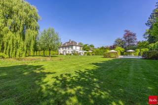 <p><strong>Met gepaste trots stellen wij u dit unieke pareltje voor, op een boogscheut van het centrum van Lier.</strong><br />Dit domein van 3.877 m² ligt uiterst landelijk en rustig, maar is tegelijk vlot bereikbaar via de E19. Zowel het stadscentrum als het Netelandschap bevinden zich op wandel- en fietsafstand.</p>
<p>De eigenaars kozen hier voor een prachtig, authentiek gebouw met hoogwaardige, natuurlijke bouwmaterialen zoals extra dikke eikenhouten vloeren, massieve houten maatwerkkasten en -deuren, en natuursteen. Met de schitterende orangerie, de fantastische tuin en het extra lange zwembad heerst hier een echt vakantiegevoel.</p>
<p>Een deel van het perceel is vergund verkaveld als bouwgrond, wat heel wat mogelijkheden biedt: een extra praktijkruimte voor een vrij beroep, een tweede woning voor een familielid of een toekomstige verkoop.</p>
<p><strong>Indeling</strong></p>
<p><strong>Gelijkvloers</strong><br />Bij het binnenkomen valt de authentieke sfeer meteen op. Vanuit de statige inkomhal met gastentoilet en vestiaire komt u rechtstreeks in de ruime leefruimte met open haard aan de ene zijde en een fantastische leefkeuken aan de andere. De woonkamer bestaat uit een stijlvolle eetkamer, een ruime living en een bibliotheek/tv-hoek in de opkamer. Dankzij de grote raampartijen en erkers baadt de ruimte in natuurlijk daglicht en geniet u van een panoramisch uitzicht op de tuin. De leefkeuken, met kookeiland en ontbijthoek, is rijkelijk uitgerust met alle nodige toestellen en massieve houten kasten. Ze biedt toegang tot een sfeervolle orangerie met directe verbinding naar het zonnige terras en de tuin.<br />Naast de keuken bevindt zich een praktische, authentieke sas/mudroom met zij-ingang, toilet, ruimte voor een douche en toegang tot de ruime wasplaats.</p>
<p><strong>Kelder</strong><br />Via de keuken bereikt u de kelder, bestaande uit 3 aparte delen: een bergkelder, een wijnkelder en een technische ruimte.</p>
<p><strong>Verdieping</strong><br />Een elegante blauw hardsteen trap leidt naar de verdieping, waar zich de master bedroom, 3 slaapkamers en 2 badkamers bevinden. De ruime master bedroom beschikt over een volledige kastenwand en een luxe marmeren badkamer, inclusief terrasje met uniek zicht op de tuin. Aan de andere zijde van de verdieping bevinden zich de 2de, 3rde en 4rde slaapkamer, waarvan twee voorzien van ingemaakte kasten. De 2de badkamer beschikt over een dubbele wastafel, bad, douche en toilet. Grote ramen zorgen ook hier voor licht en zicht op de tuin.</p>
<p><strong>Zolder</strong><br />Via een vaste, mooie eiken trap bereikt u de volledig geïsoleerde zolder, waar ruimte is voor minstens drie extra slaapkamers en een badkamer (leidingen reeds voorzien).<br /><br /><strong>Buiten<br /></strong>De prachtig aangelegde volwassen parktuin beschikt over meerdere terrassen, zodat u op elk moment van de dag kunt genieten van de zon. Het extra lang verwarmd zwembad met ruime terrassen en een schaduwtent maakt het plaatje compleet. Achteraan ter hoogte van het zwembad bevindt zich een serre, dewelke dienst doet als technische ruimte en kleedruimte met daarnaast een buitendouche. Praktisch is ook het ruime bijgebouw, ideaal voor fietsen en extra opbergmogelijkheden.<br /><br /><strong>**De woning is momenteel gelegen op 2 bouwgronden. <span>Er bestaat bijgevolg de mogelijkheid om de villa aan te kopen zonder de naastliggende bouwgrond, </span>die vandaag volledig als tuin wordt gebruikt. </strong></p>
<p><strong><br />Bijzonderheden</strong></p>
<ul>
<li>Gebouwd met oog voor kwaliteit en vakmanschap</li>
<li>Extra hoge plafonds met sierlijsten</li>
<li>Gunstig EPC</li>
<li>Ruime kelder</li>
<li>Prachtige parktuin</li>
<li>12m verwarmd zwembad met warmtepomp</li>
<li>Geïsoleerde zolder met talrijke mogelijkheden</li>
<li>360° groen!</li>
</ul>
Voor meer informatie of een bezoek van deze prachtige woning kan u contact nemen met Sigalit via Sigalit@reds.be of op 0475668474