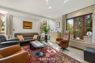 Voor meer info en foto’s, surf naar www.swevers.be – Deze ruime open bebouwing aan de Koerselsesteenweg 146 in Beringen combineert comfortabel wonen met professionele mogelijkheden. Dankzij aparte ingangen voor het privé- en praktijkgedeelte is de woning ideaal voor een zelfstandige activiteit aan huis, maar ook geschikt voor kangoeroewonen. De woning dateert van 1980 en werd doorheen de jaren gericht vernieuwd, met onder meer een nieuw pannendak, gerenoveerde living en keuken, vernieuwde condensatieketel, drie nieuwe Veluxramen en zonnepanelen uit 2023. Met een bewoonbare oppervlakte van 340 m² is er bijzonder veel ruimte. Op het gelijkvloers bevinden zich een woonkamer met eetkamer van samen 46 m², een keuken van 16,40 m², bureau en apart toilet. Het praktijkgedeelte omvat een wachtruimte, consultatieruimte, archief/doka en eigen toilet. Daarnaast zijn er een inpandige garage van 42 m² en een ruime berging. De eerste verdieping telt vier slaapkamers van 12,5 tot 22 m², waarvan één met terras en één met ingemaakte kasten. Verder zijn er een badkamer en apart toilet. De kelder van 44 m² zorgt voor extra bergruimte. Het perceel van 37a 75ca beschikt over een groen aangelegde tuin met meerdere terrassen en tuinhuisjes. Er is parkeerruimte voor 8 à 10 wagens. Scholen, openbaar vervoer en de snelweg zijn vlot bereikbaar. Extra troeven zijn het alarmsysteem, rolluiken, zonnewering en een beveiligde deur. Voor meer informatie, bel 011 255 155. Bron bewoonbare oppervlakte: EPC – verslag.