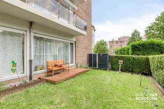 <strong>Immo Van Middelem verkoopt dit ruime (+/- 115 m²), instapklare gelijkvloers appartement met 2 kamers, zuid-geöriënteerde tuin, kelder en ondergrondse staanplaats, op wandelafstand van het CENTRUM van Dilbeek.</strong><br /><br />Het is gelegen op de GELIJKVLOERSE verdieping van goed onderhouden gebouw in een rustige woonwijk met uitsluitend plaatselijk verkeer. Op wandelafstand vind je winkels, scholen, restaurants en openbaar vervoer. De Brusselse Ring ligt op amper 1,5km. Een TOPLOCATIE, dus! <br /><br />De indeling is als volgt:<br />- ruime inkomhal met vestiaire en WC, badkamer met douche in bad, slaapkamer 1 met toegang tot de tuin, grote living (salon en eetplaats) met toegang tot de tuin, keuken met berging.<br />- via een trap in de living daalt u af naar slaapkamer 2 (kelderniveau).<br />- op de -1 beschikt u nog over een gemeenschappelijke wasplaats, een fietsenstalling, een privatieve kelderruimte en een privé-staanplaats. <br /><br />Gemeenschappelijke lasten: ± 120/maand<br />- onderhoud en schoonmaak gemene delen + lift;<br />- voorschot verbruik water;<br />- blokpolis;<br />- syndicus;<br /><br />Centrale verwarming op elektriciteit. <br />EPC: 348 kWh/m².jaar - Label D (UC: 2898664). <br />Elektriciteit CONFORM tot 2051! <br />Vrij bij akte.