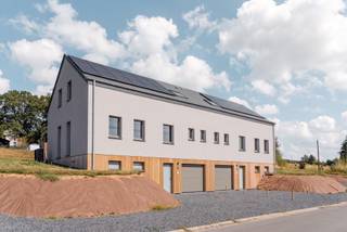 Op enkele minuten van Bastogne, in het hart van Saint-Ode, verenigt dit recente vastgoedcomplex twee geschakelde huizen met elk ongeveer 180 m² woonoppervlakte op een perceel van bijna 2.000 m². Deze configuratie biedt een interessante combinatie van residentieel erfgoed, flexibiliteit in gebruik en verhuurpotentieel.<br /><br />Elke woning biedt een ruime, lichte woonkamer, een volledig uitgeruste keuken, vier slaapkamers en twee badkamers. De leefruimtes komen uit op een terras en een eigen tuin, terwijl een garage met een gemotoriseerde deur elke eenheid completeert. De indeling maakt verschillende erfgoedstrategieën mogelijk: familiebewoning, intergenerationele co-housing of verhuur van beide woningen.<br /><br />Elk huis is voorzien van 12 zonnepanelen, hoogwaardige PVC-ramen, leistenen dakbedekking en een alarmsysteem. Verschillende apparaten zijn op afstand te bedienen. Gelegen in een residentiële en groene omgeving, blijft het complex goed bereikbaar naar Bastogne, voorzieningen en belangrijke wegen. Een zeldzame residentiële configuratie, die de koper de mogelijkheid biedt om een vastgoedportefeuille op te bouwen of te diversifiëren binnen één complex.